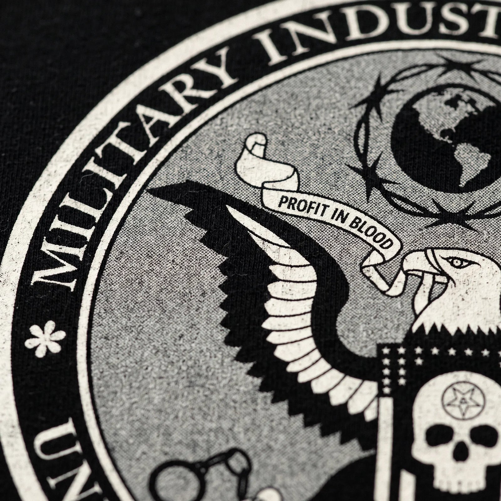 Close-up of distressed Military Industrial Complex seal graphic on black boxy T-shirt