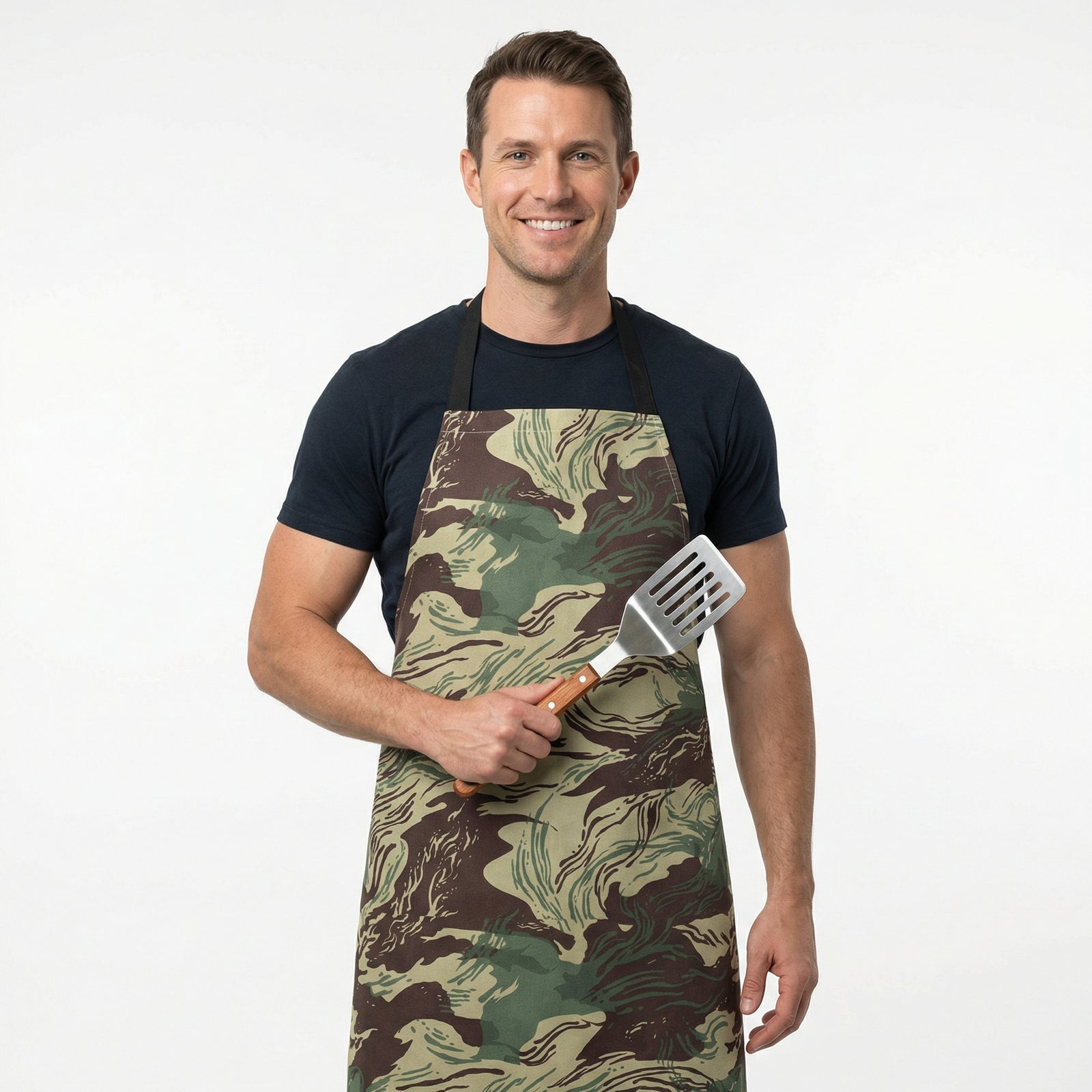 Man wearing a camouflage apron holding a spatula on a white background