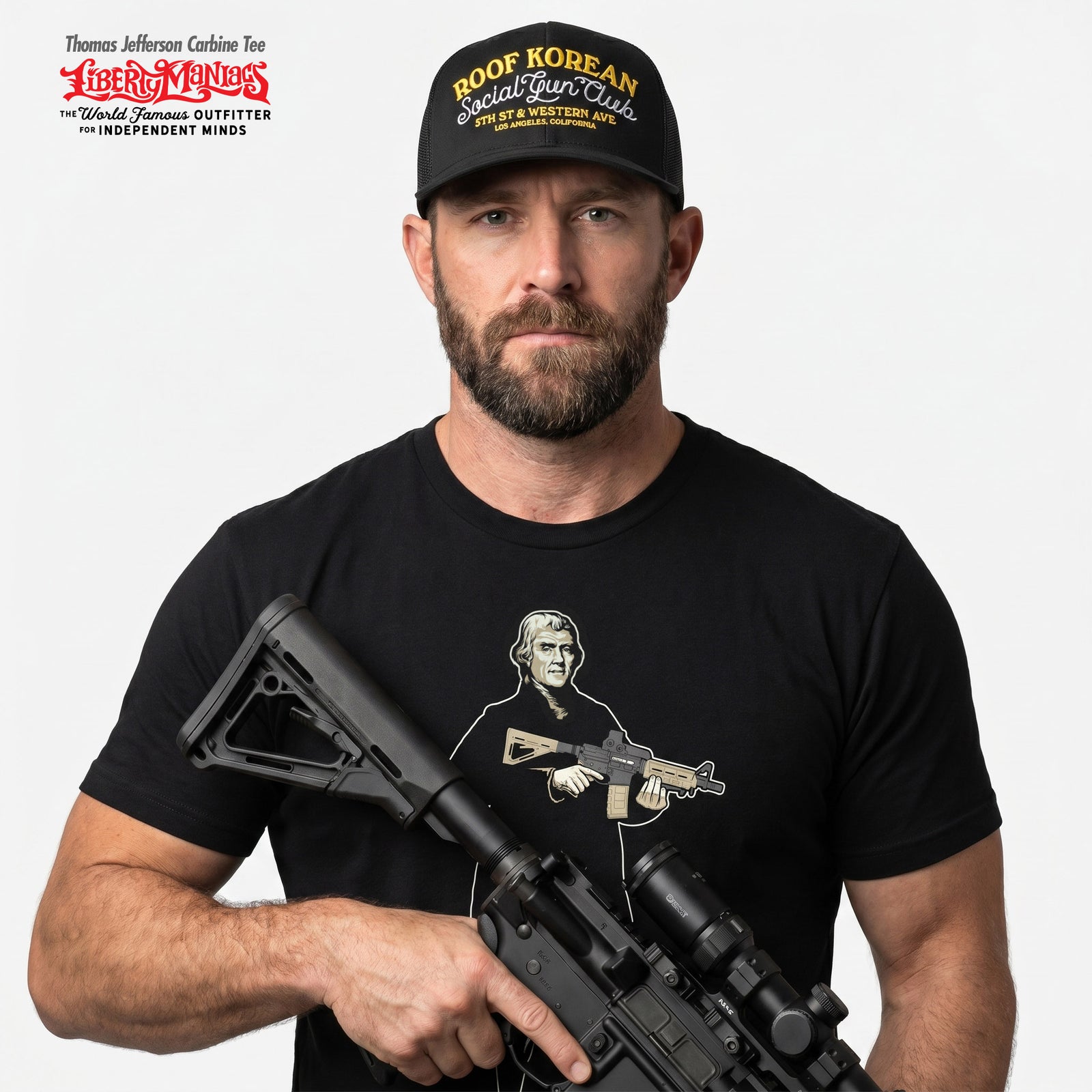Man wearing a black Thomas Jefferson With a Carbine t-shirt with a cap Liberty Maniacs trucker hat on that says Roof Korean Social Gun Club, holding a rifle on a white background.