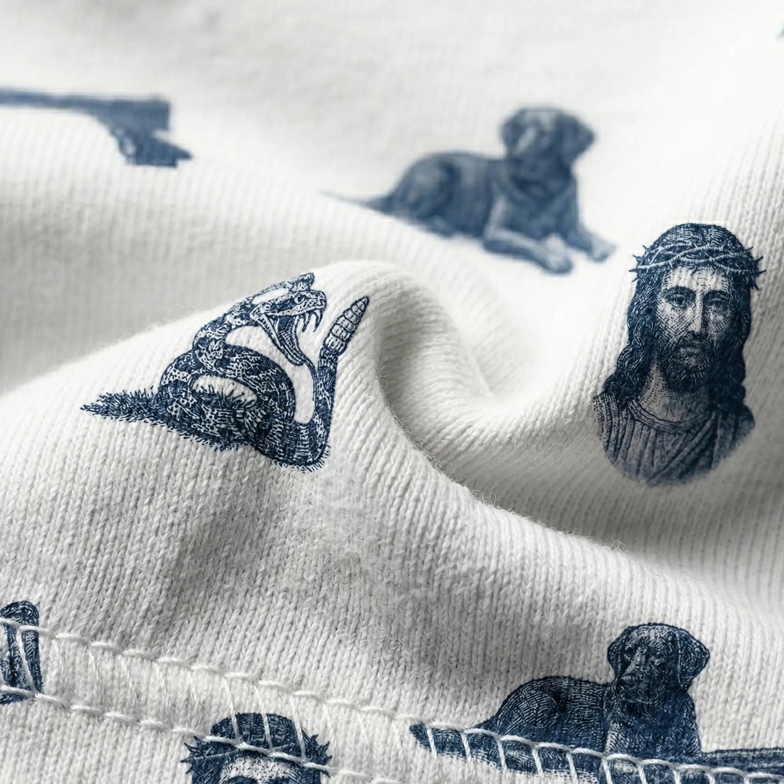 White fabric with black ink illustrations of a snake, a head, and a dog.