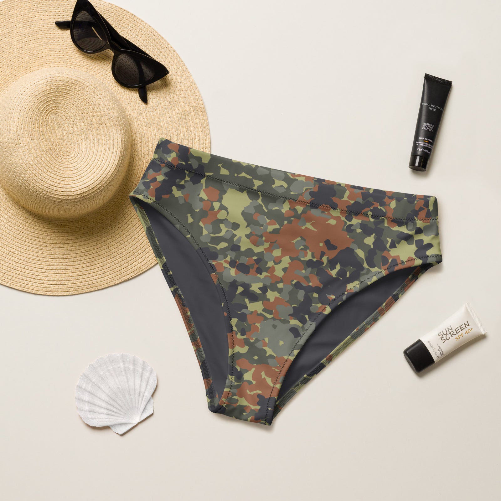 Camouflage swimsuit bottom with sun hat, sunglasses, and sunscreen on a light background