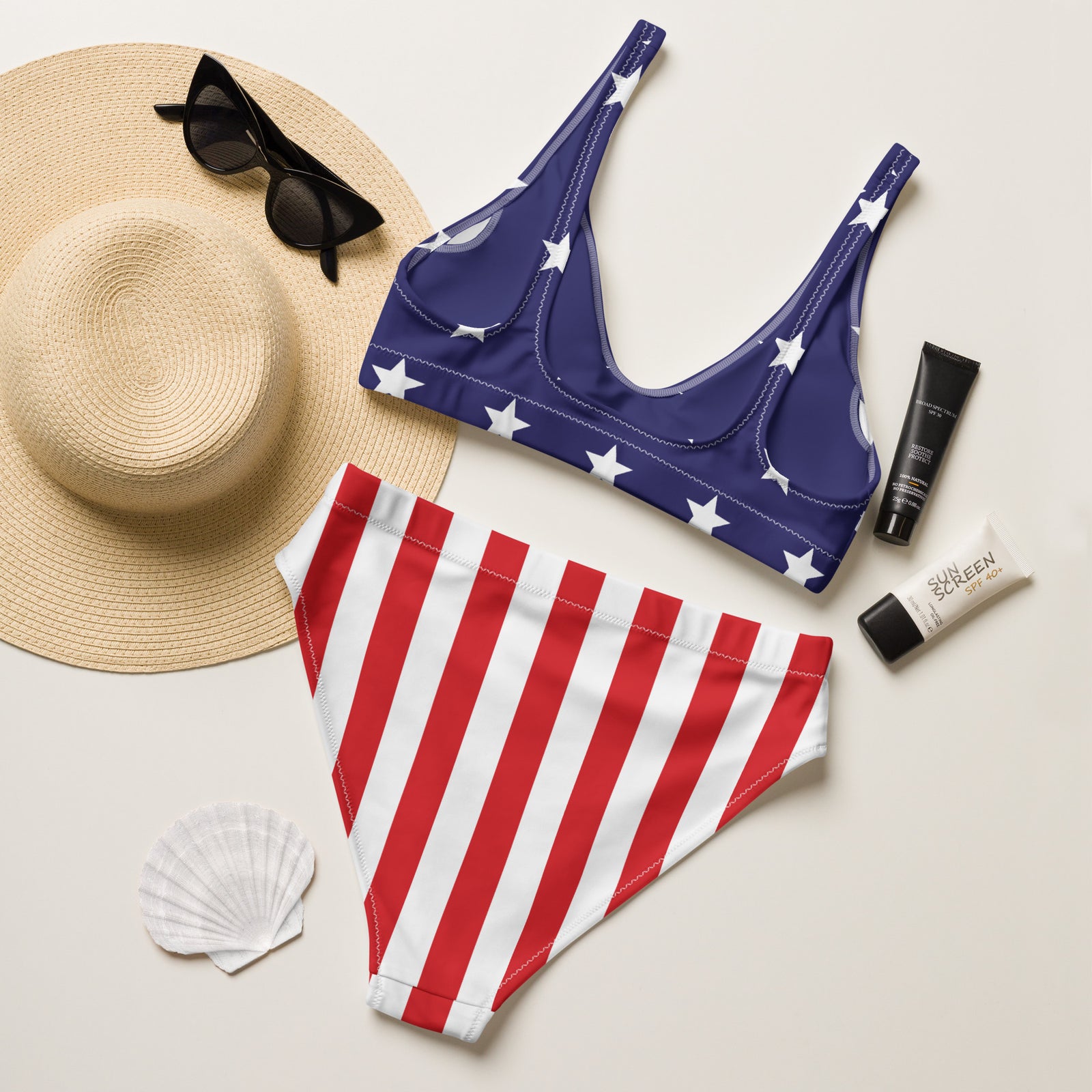 American flag bikini set with sun hat, sunglasses, sunscreen, and shell on a light background