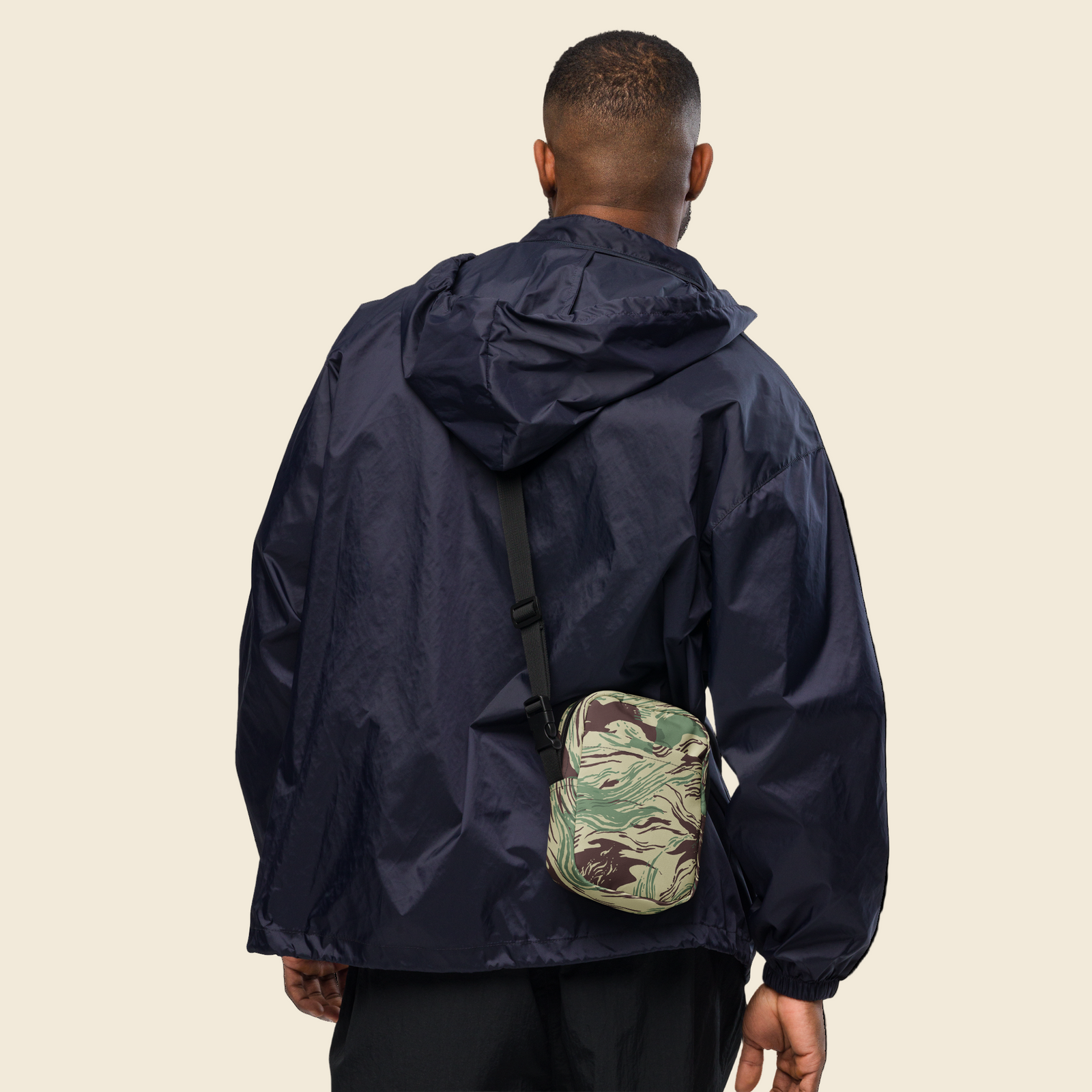 Person wearing a navy raincoat with a camouflage bag on a white background