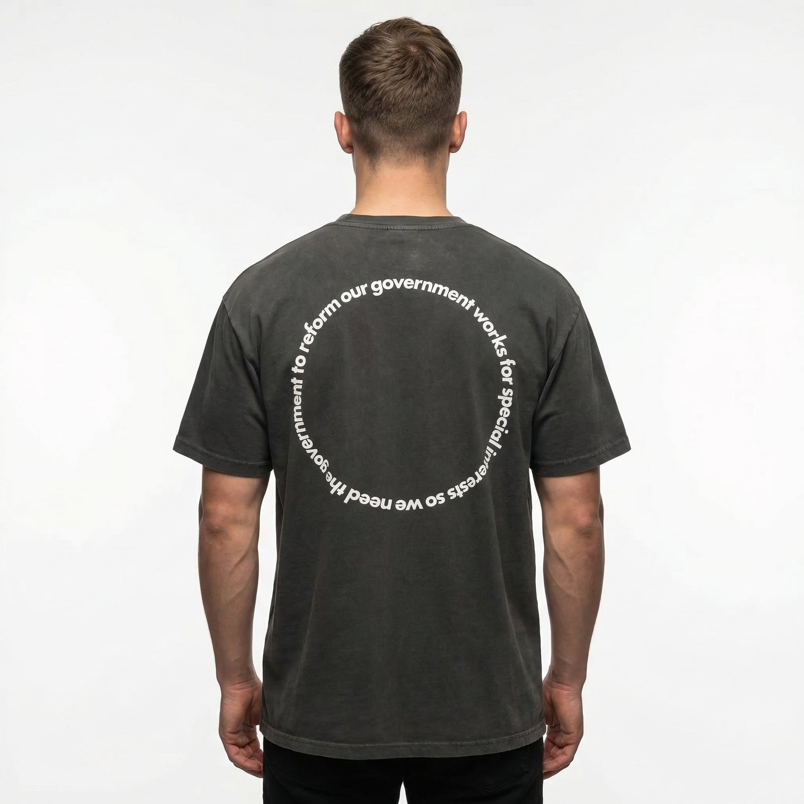 Man wearing a black vintage-style t-shirt with circular text design about government and special interests printed on the back