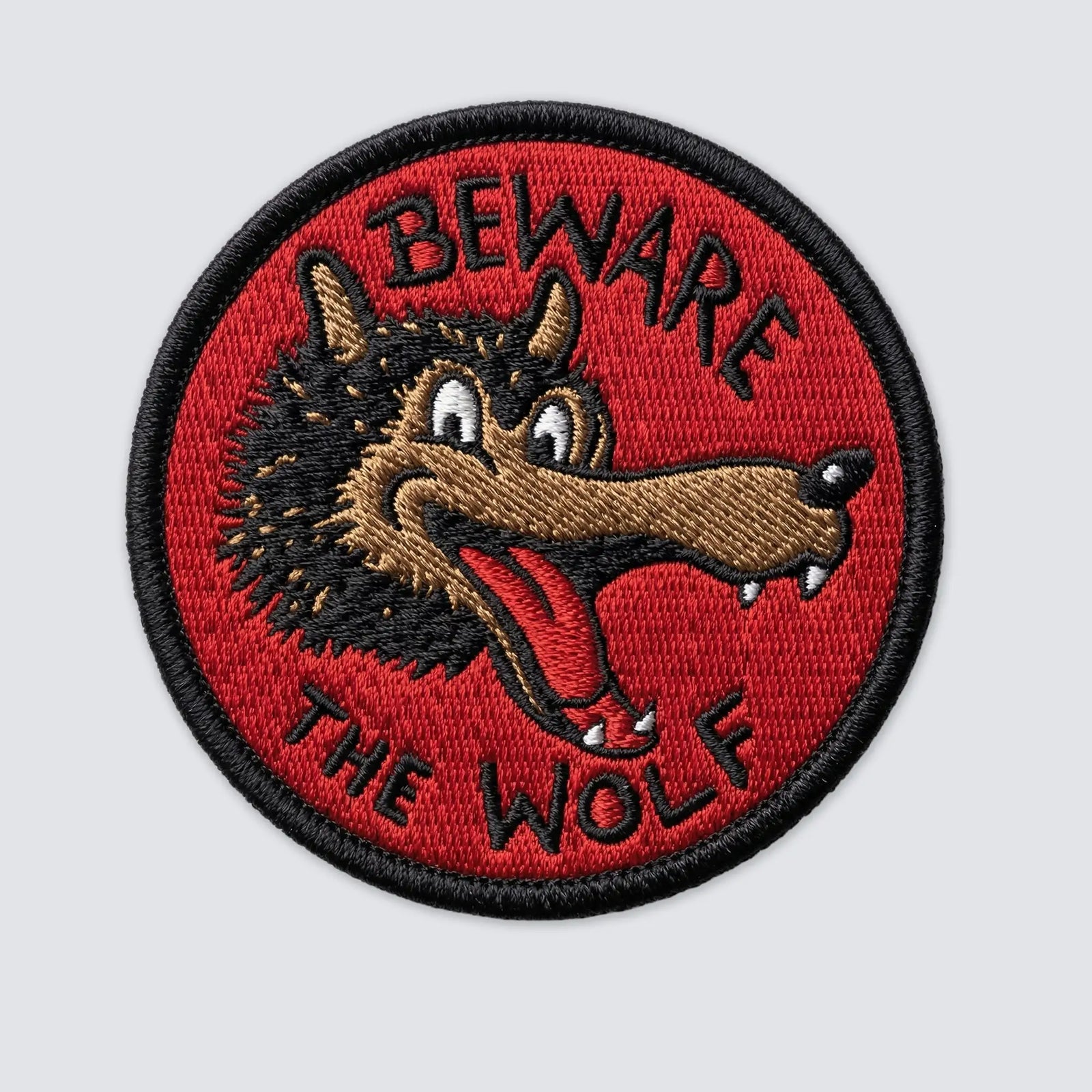 Embroidered patch with a wolf design and 'Beware the Wolf' text on a red background.