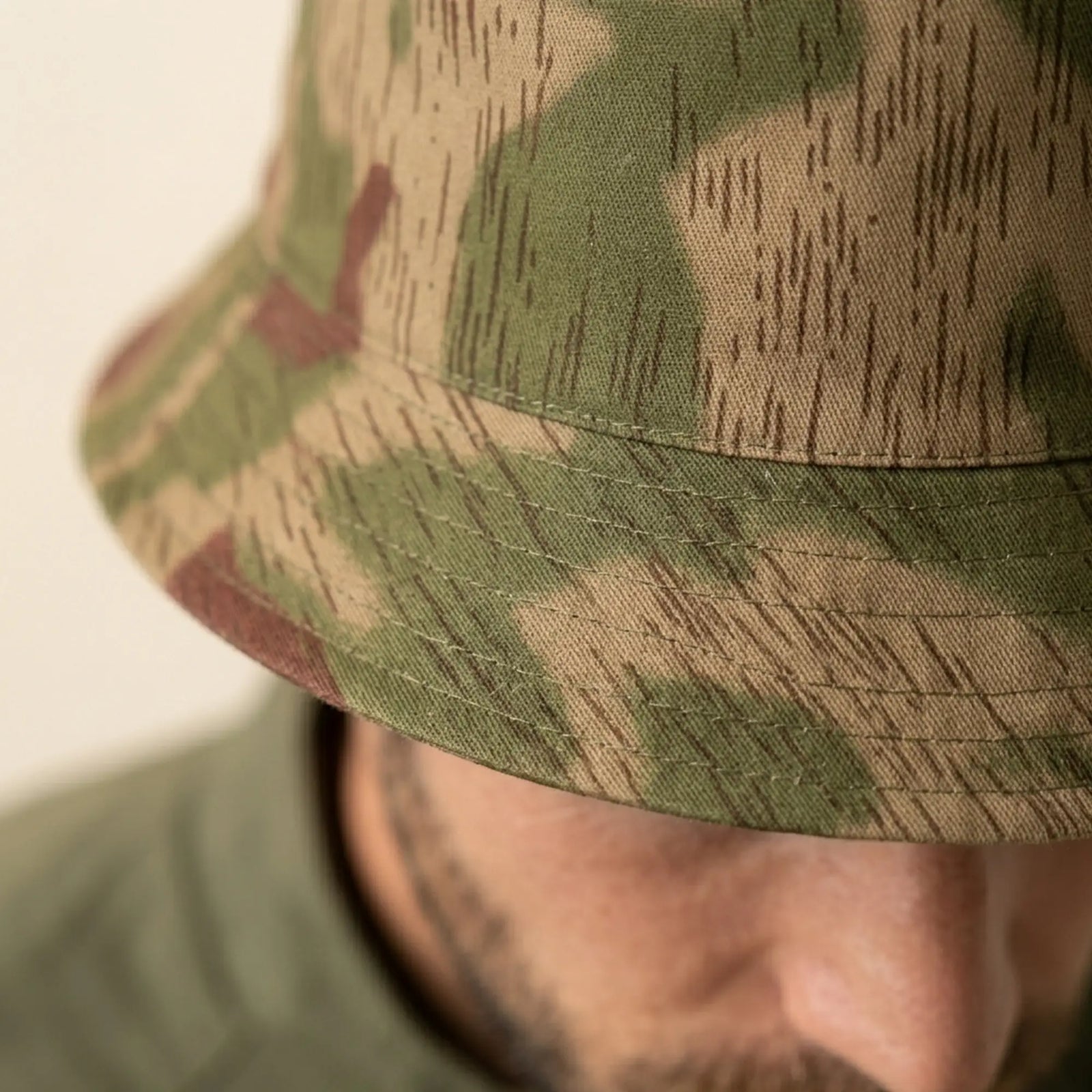 Close-up of a person wearing a camouflage bucket hat.