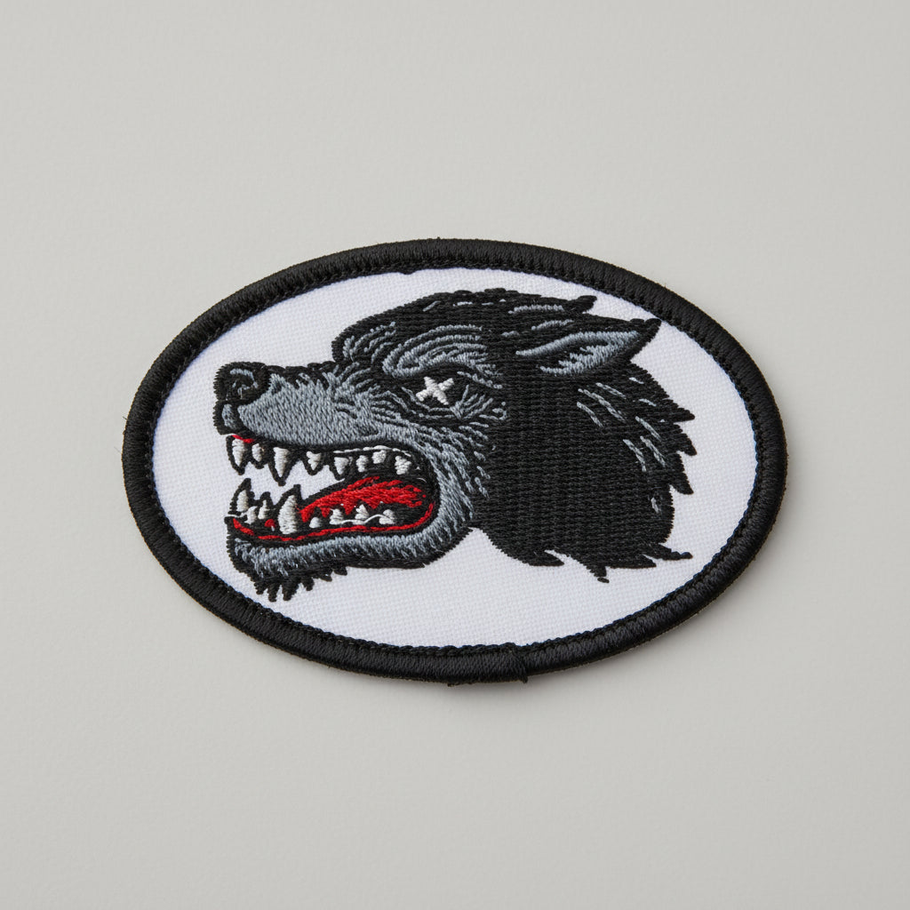 Embroidered patch of a wolf head with an open mouth on a white background