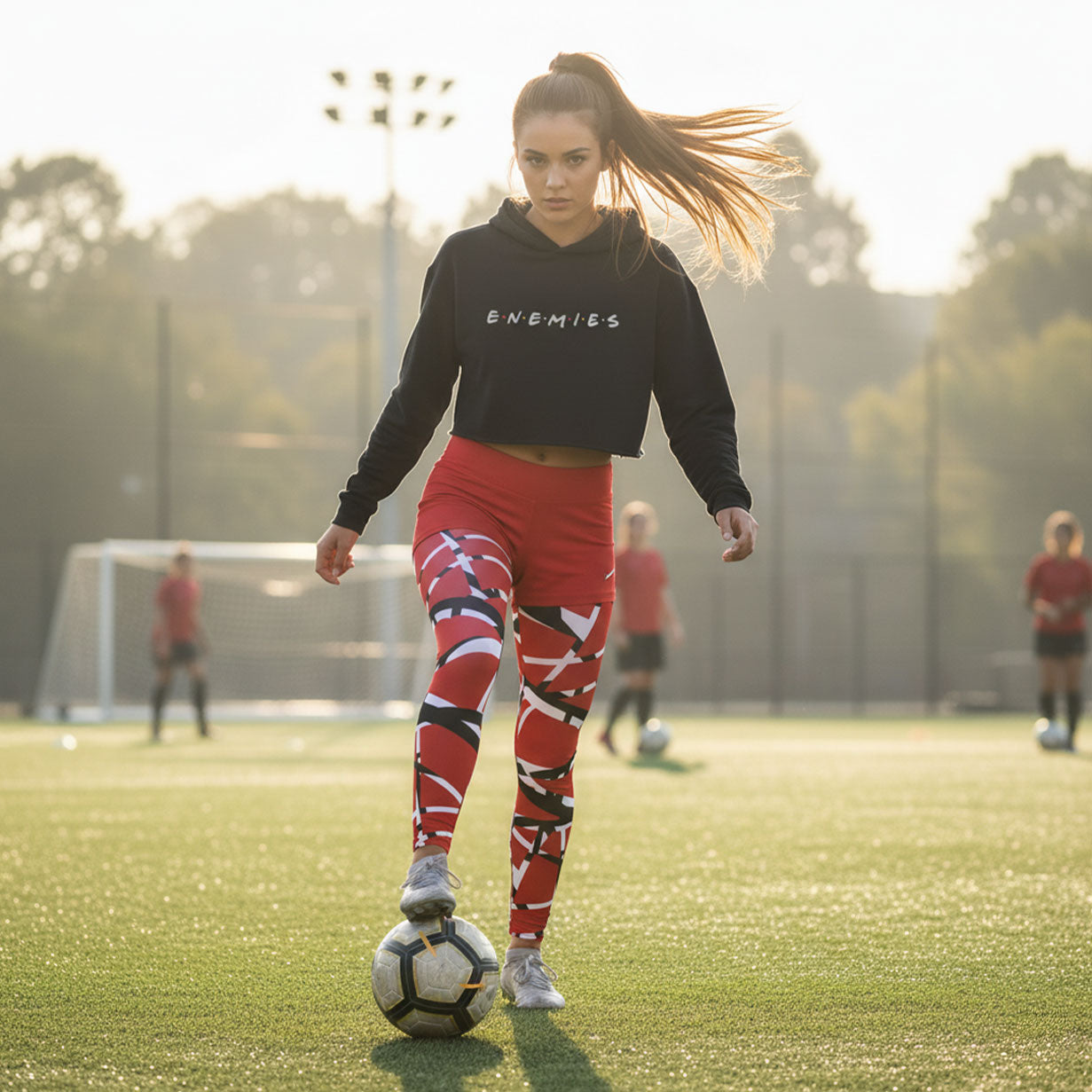 Woman in black sweatshirt and red leggings with soccer ball on a field