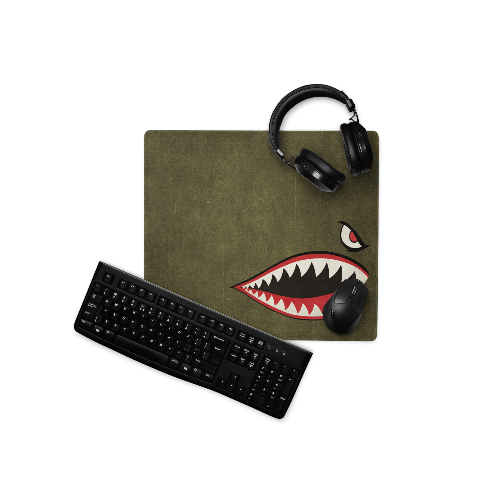 Desk setup with a green mouse pad featuring a shark design, black keyboard, and black headphones on a white background.