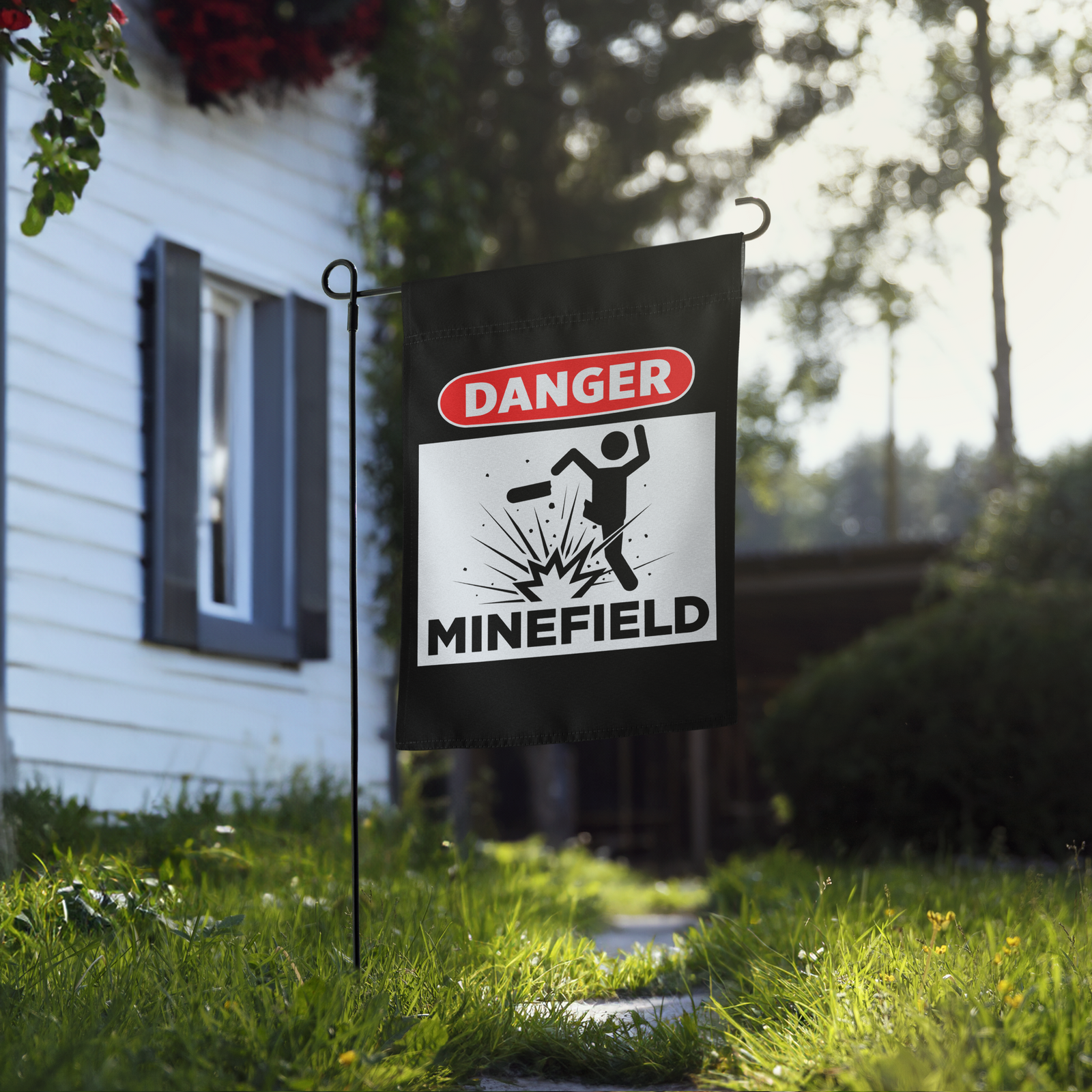 Garden flag with 'Danger Minefield' warning sign in front of a house
