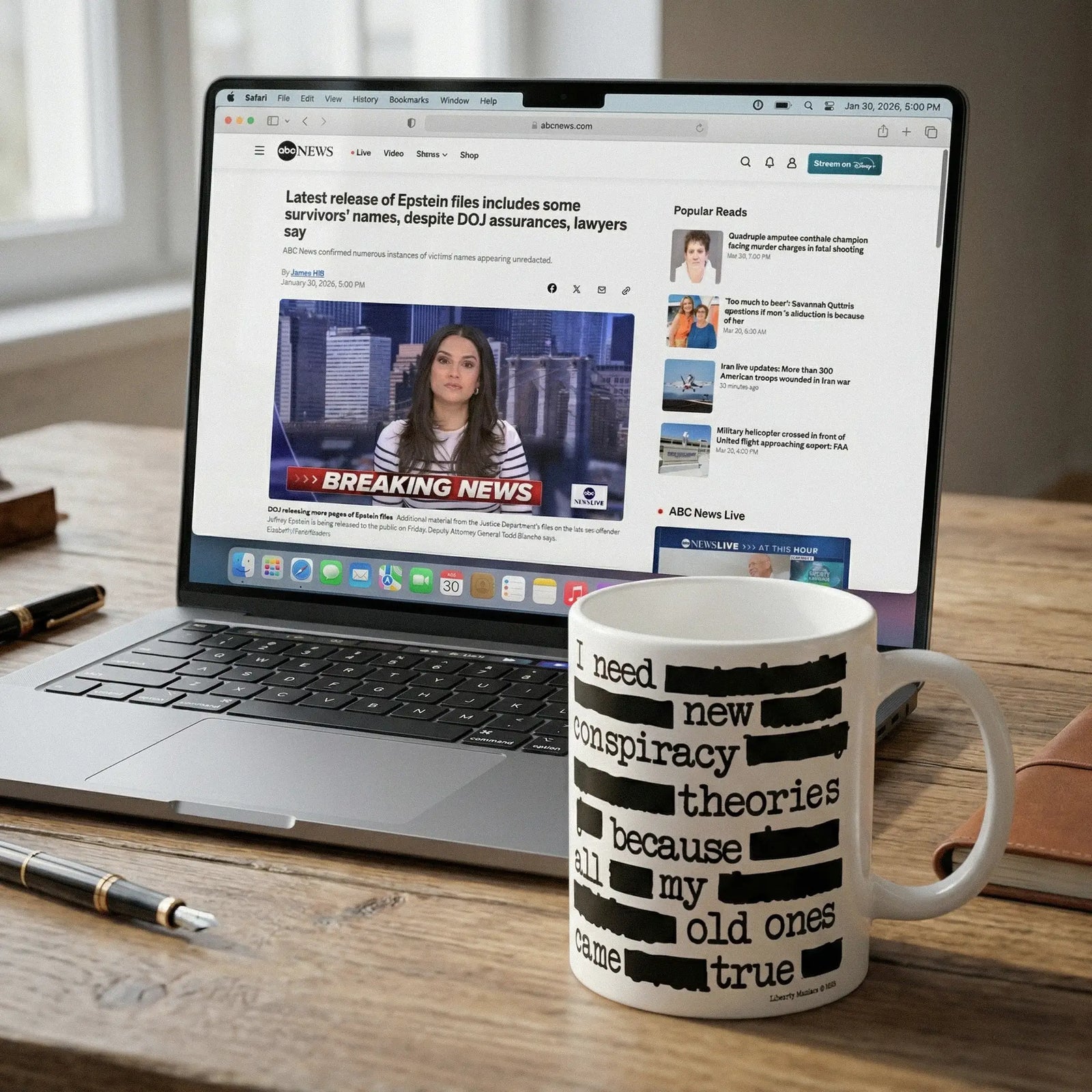 Laptop on a desk with a mug displaying text next to it depicting a humorous conspiracy theory statement "I need new conspiracy theories because all my old ones came true."