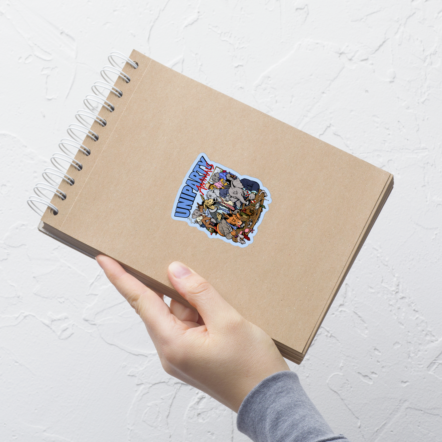Hand holding a brown notebook with a sticker on a white textured surface