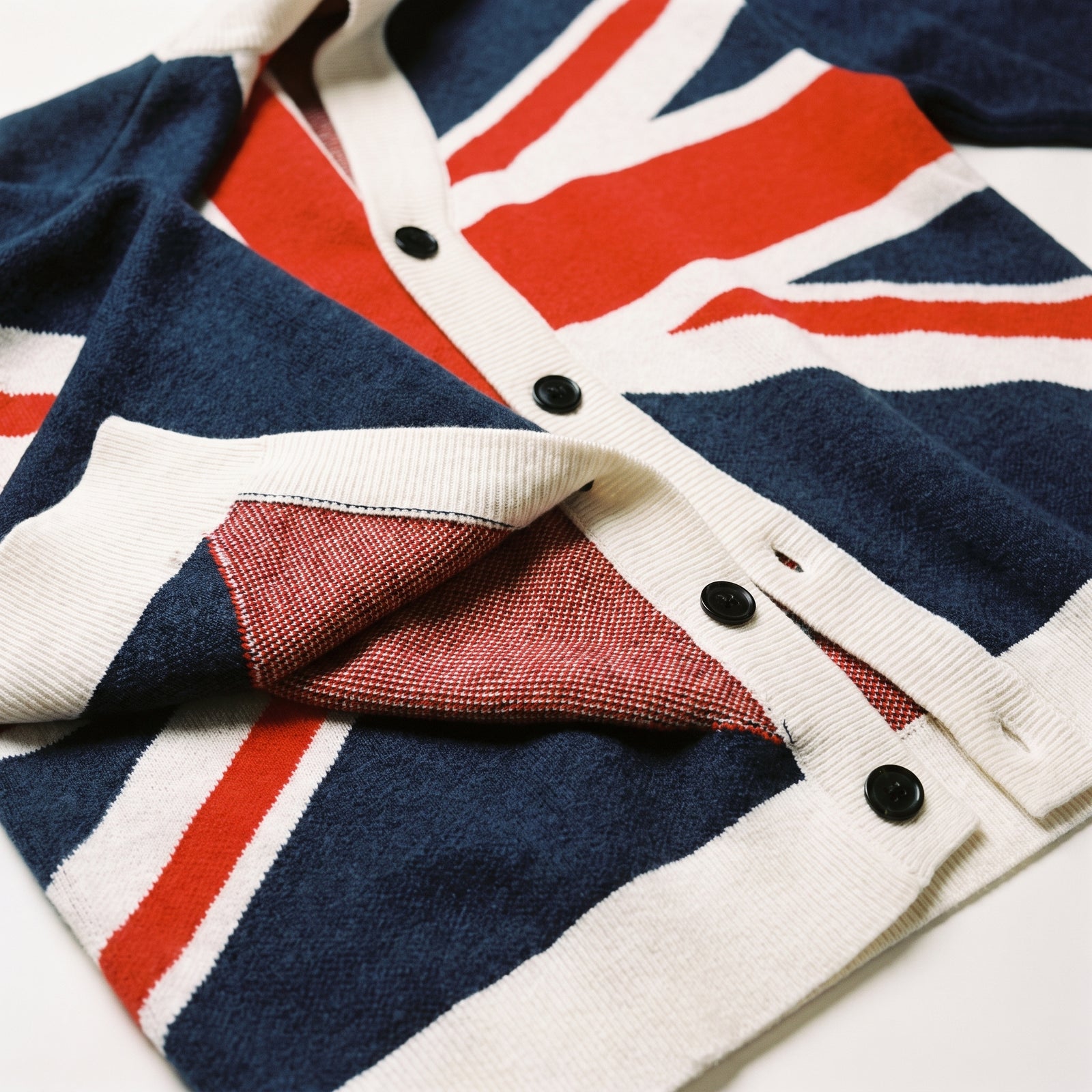 Close-up of the Union Jack cardigan jacquard knit, ribbed trim, buttons, and knitted flag detail.