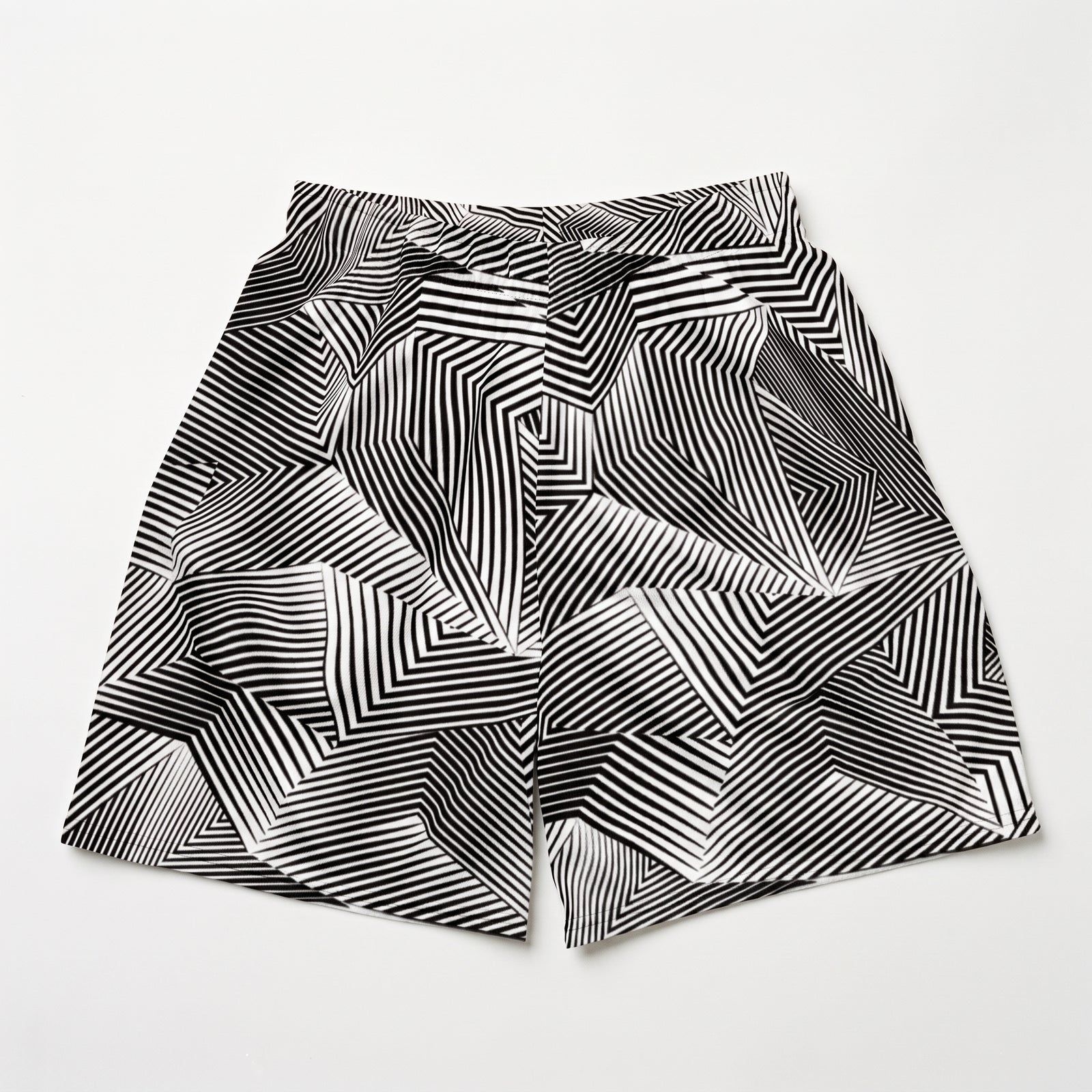 Black and white geometric patterned shorts with an abstract optical illusion stripe design, laid flat on a light gray background.