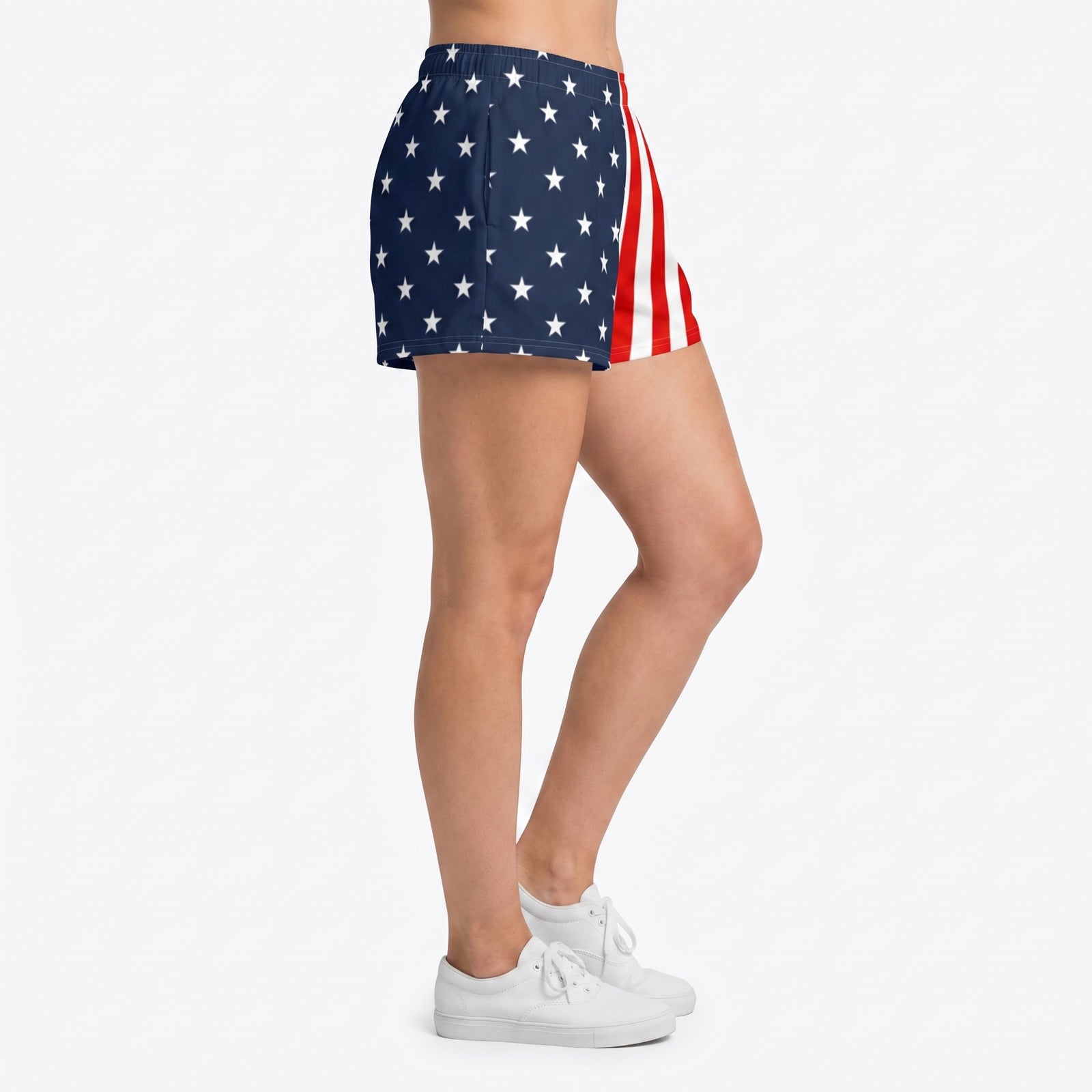 A person wearing high-waisted shorts with an American flag print, featuring white stars on a navy blue background and red and white vertical stripes, paired with white sneakers against a light gray studio background.