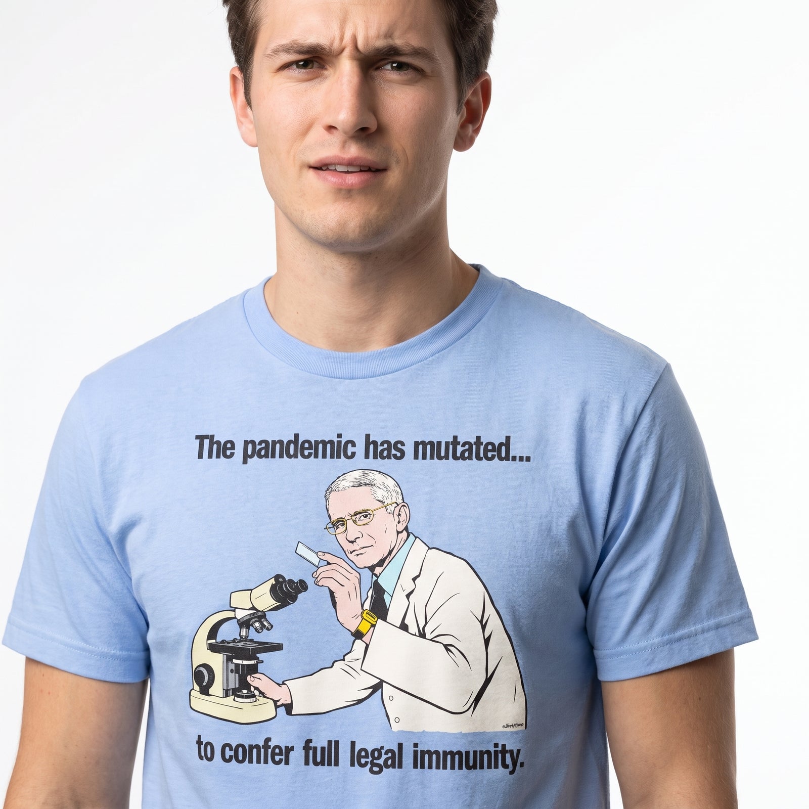A man wearing a light blue graphic t-shirt with a cartoon illustration of a scientist looking through a microscope and the text 'The pandemic has mutated.
