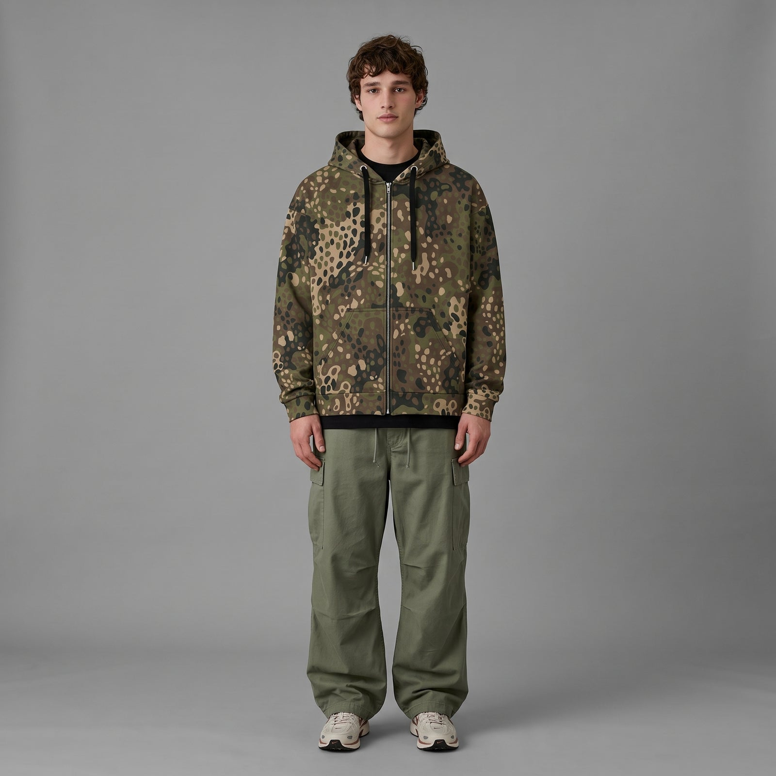 Man wearing the Erbsenmuster Pea Dot Field Green camo zip hoodie, full-length view