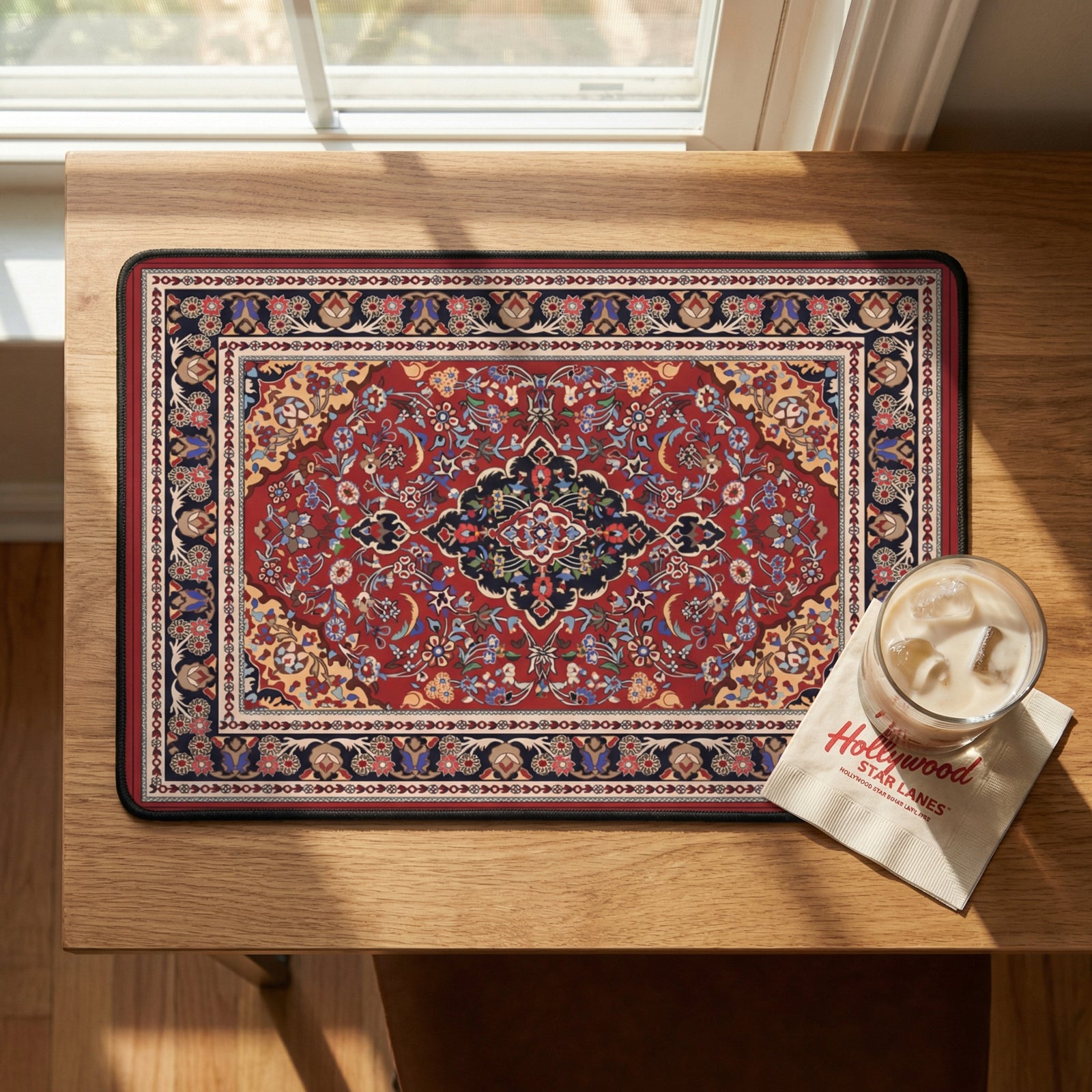 Decorative placemat with intricate design on a wooden table next to a glass of iced coffee.
