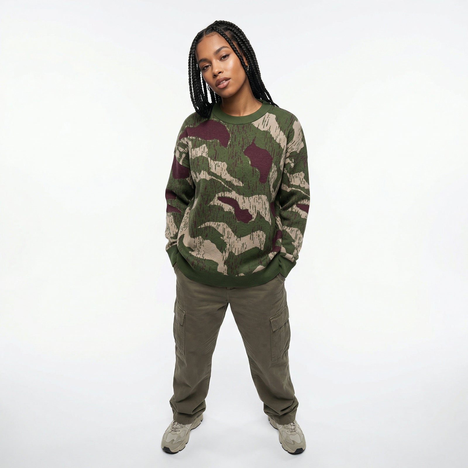 Person wearing a camouflage sweater and cargo pants on a white background