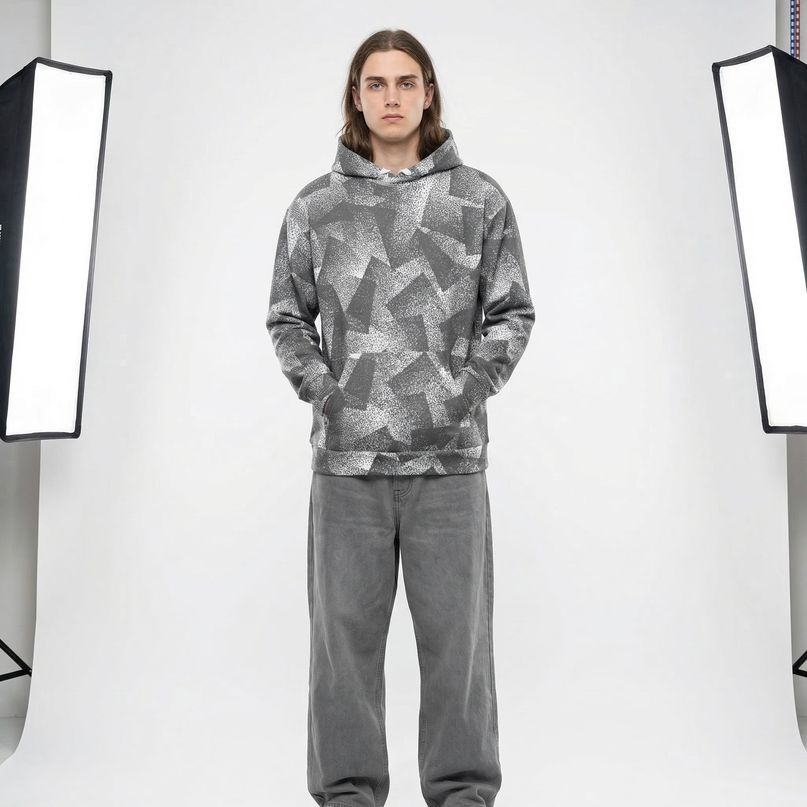 Person wearing a gray patterned hoodie and pants in a studio setting with lighting equipment.