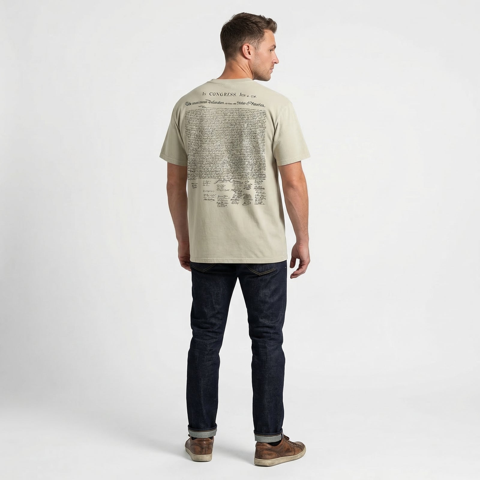 Man wearing a beige t-shirt with text on the back, standing against a white background