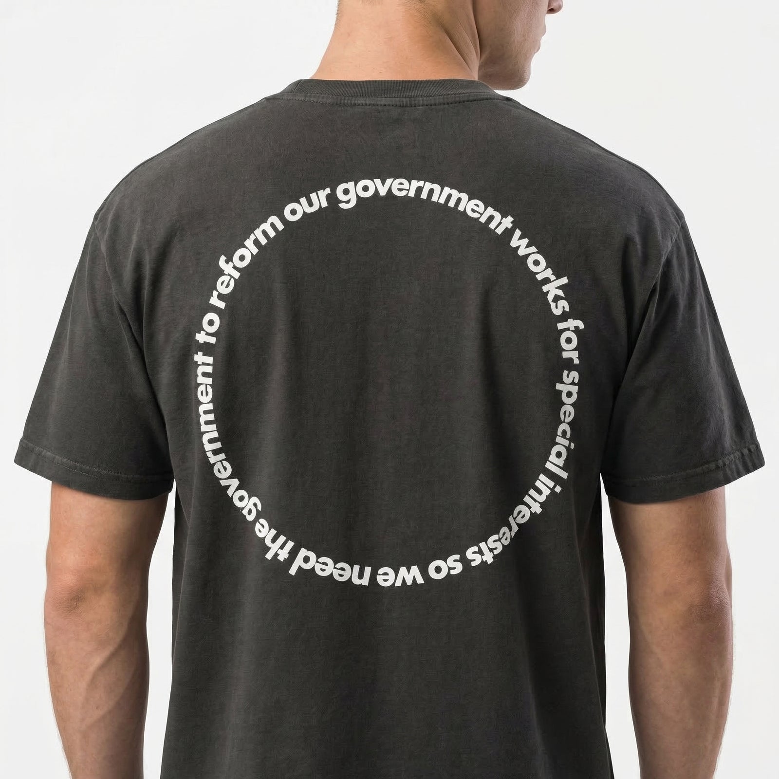 Man wearing a black vintage-style t-shirt with circular text design about government and special interests printed on the back