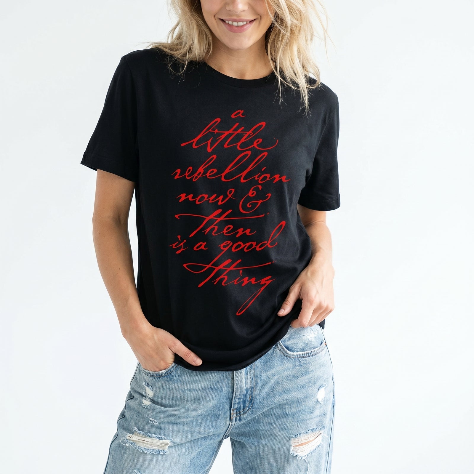 Person wearing a black t-shirt with Thomas Jefferson revolution quote red text and ripped jeans on a white background