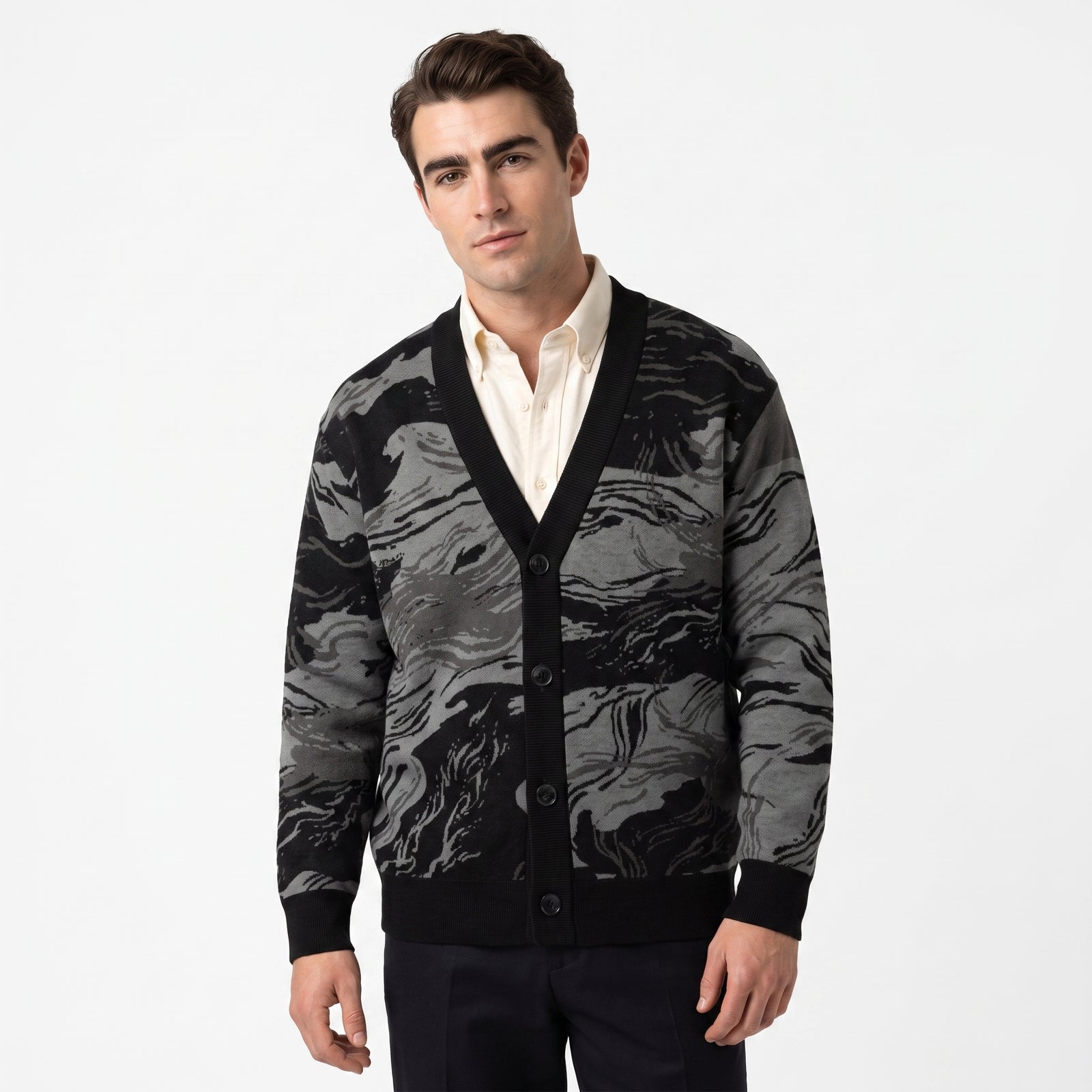Man wearing a black and gray patterned cardigan over a white shirt on a white background
