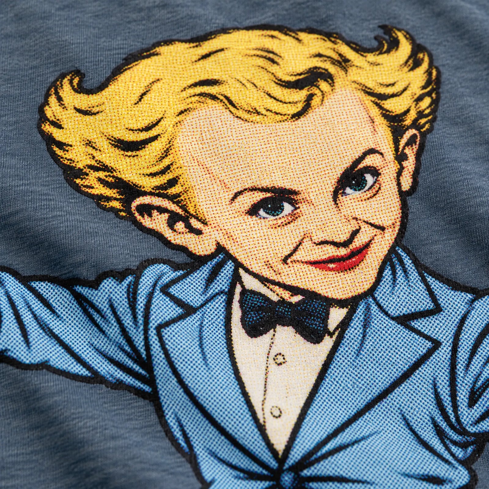 Macro of the Rumpelstiltskin print on Heather Slate cotton, showing retro color halftone dots and fine fabric texture.