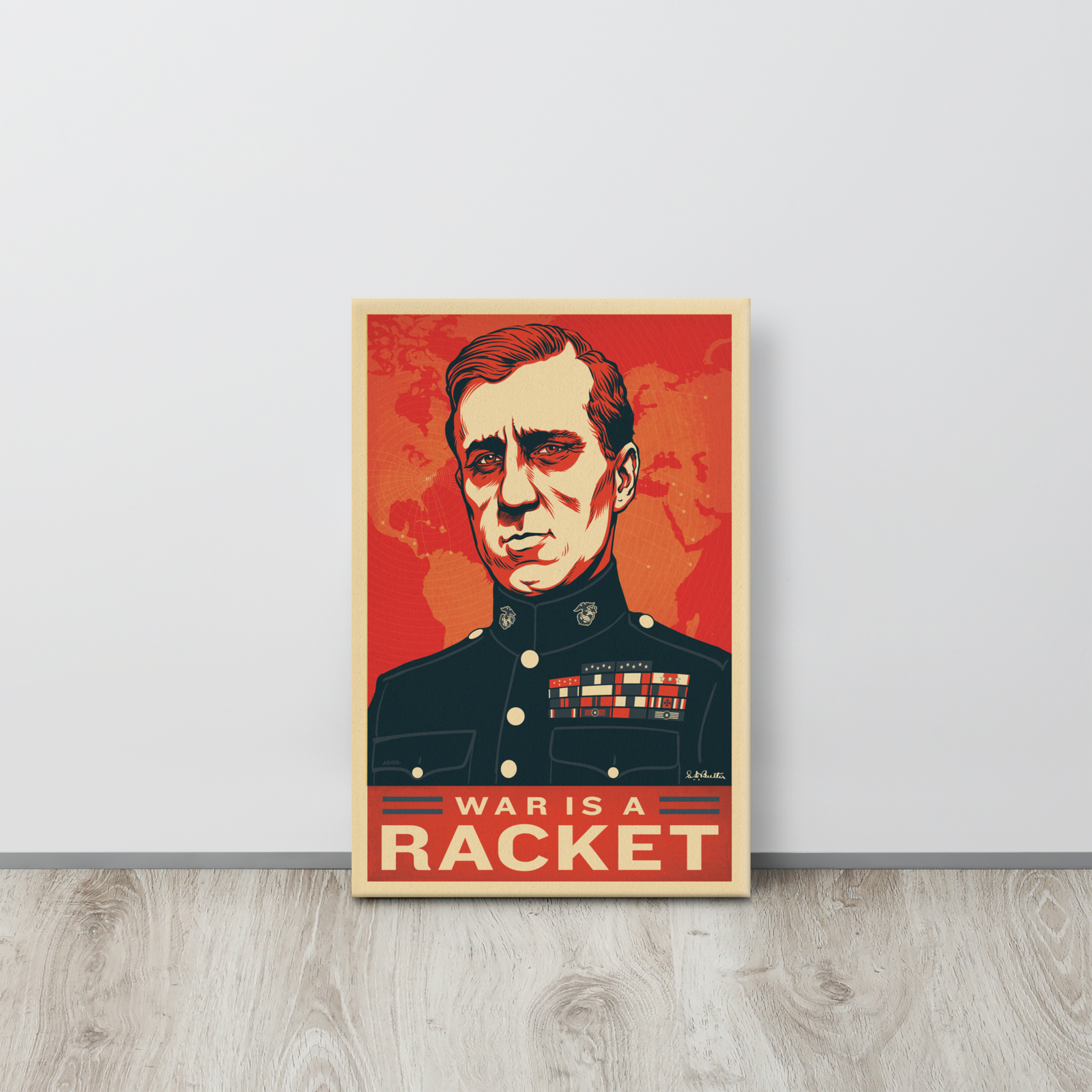 Poster with a portrait and 'War is a Racket' text on a red background, leaning against a light gray wall.