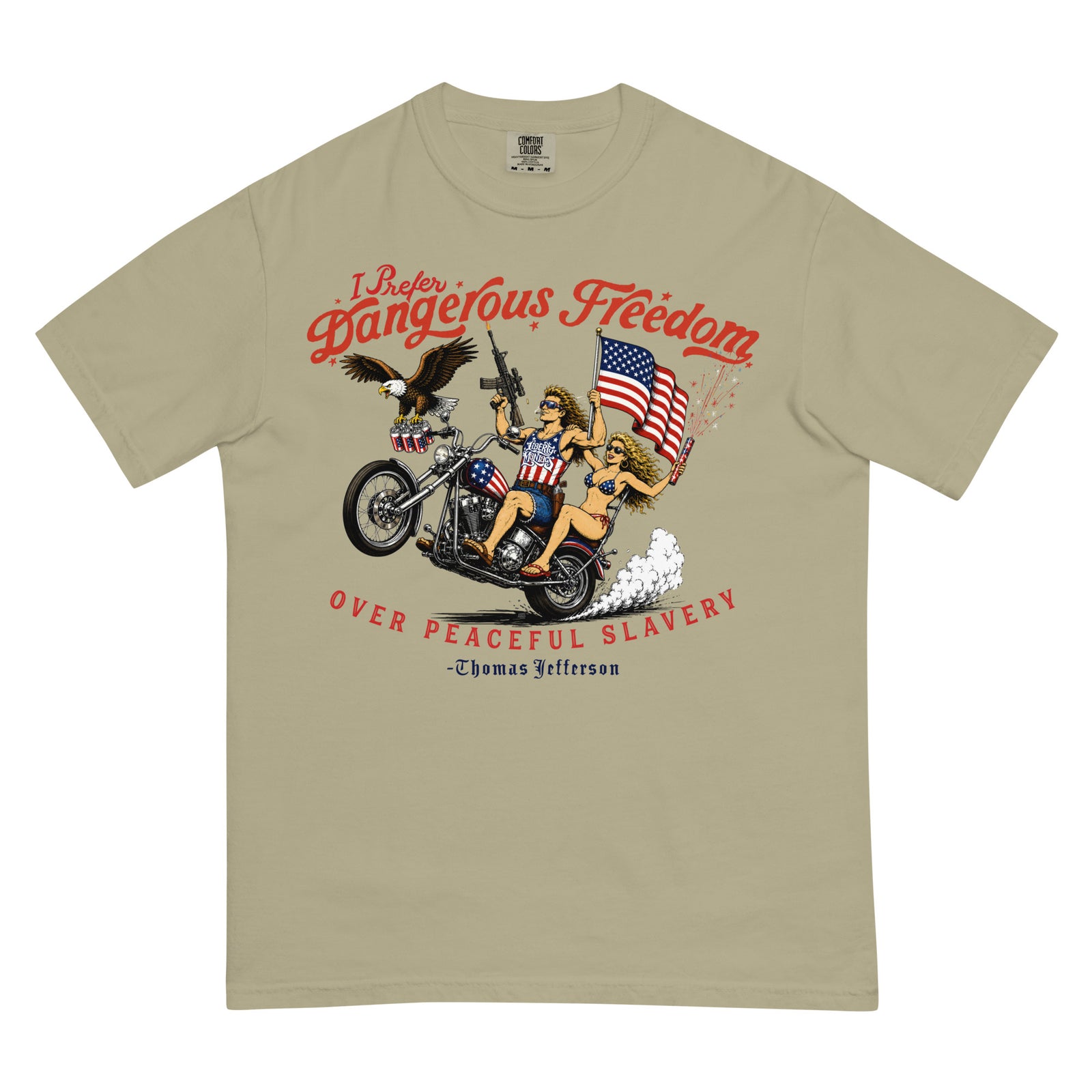 A khaki short-sleeve t-shirt with a featuring a retro-style illustration of a man and women on a motorcycle with American flags, an eagle, and fireworks. Red text above reads 'I Prefer Dangerous Freedom' and text below reads 'OVER PEACEFUL SLAVERY -Thomas Jefferson'. By Liberty Maniacs