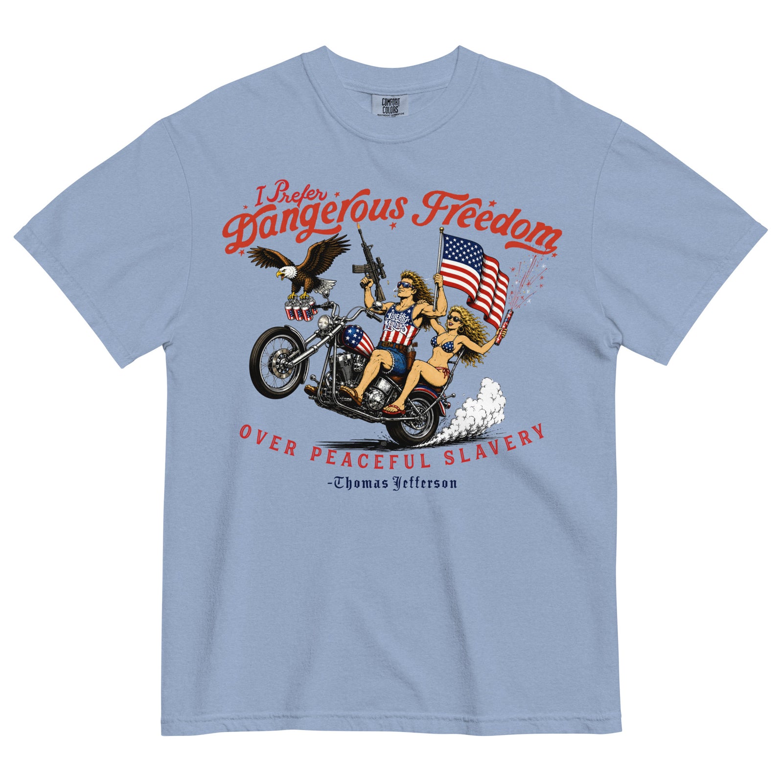 A light blue crewneck t-shirt featuring a retro-style illustration of a man and women on a motorcycle with American flags, an eagle, and fireworks. Red text above reads 'I Prefer Dangerous Freedom' and text below reads 'OVER PEACEFUL SLAVERY -Thomas Jefferson'. By Liberty Maniacs