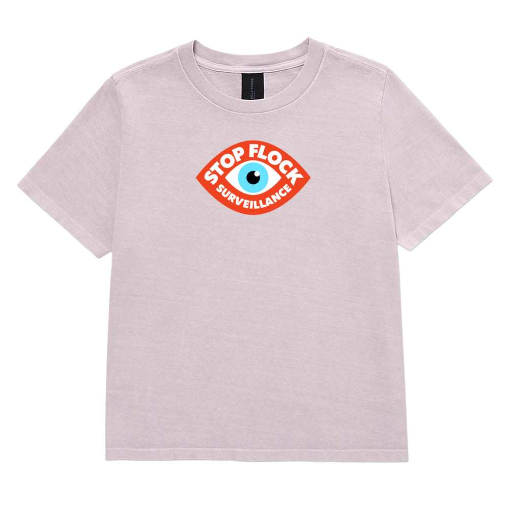 A light pink heathered short-sleeve t-shirt with a central graphic of an eye inside a red shield containing the text 'STOP FLOCK SURVEILLANCE'.