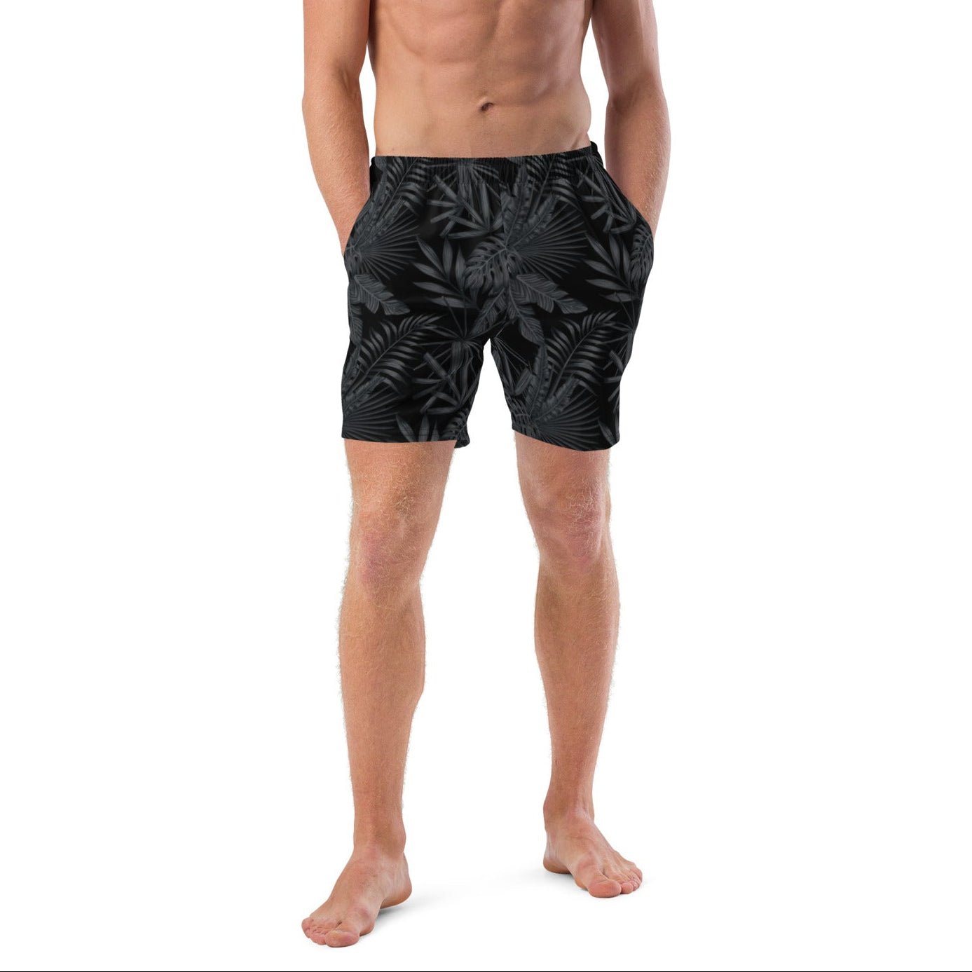 Man wearing black swim shorts with green and yellow patterns on a white background