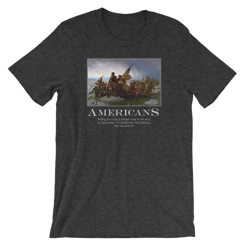 a heather dark-grey t-shirt from Liberty Maniacs. The t-shirt features a large graphic of the historical painting "Washington Crossing the Delaware." Below the painting, the word "AMERICANS" is written in a large, bold font. Underneath, smaller text reads: "Willing to cross a frozen river to kill you in your sleep. On Christmas. Not kidding. We've done it."