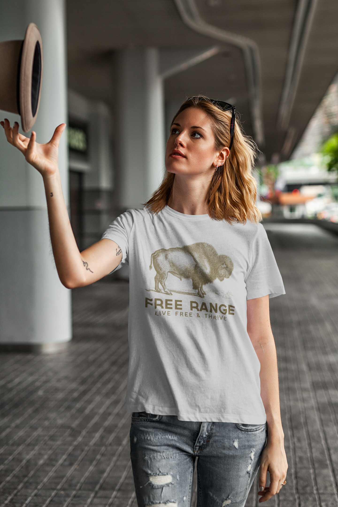 Woman wearing a light grey Free Range Live Free bison graphic T-shirt outdoors