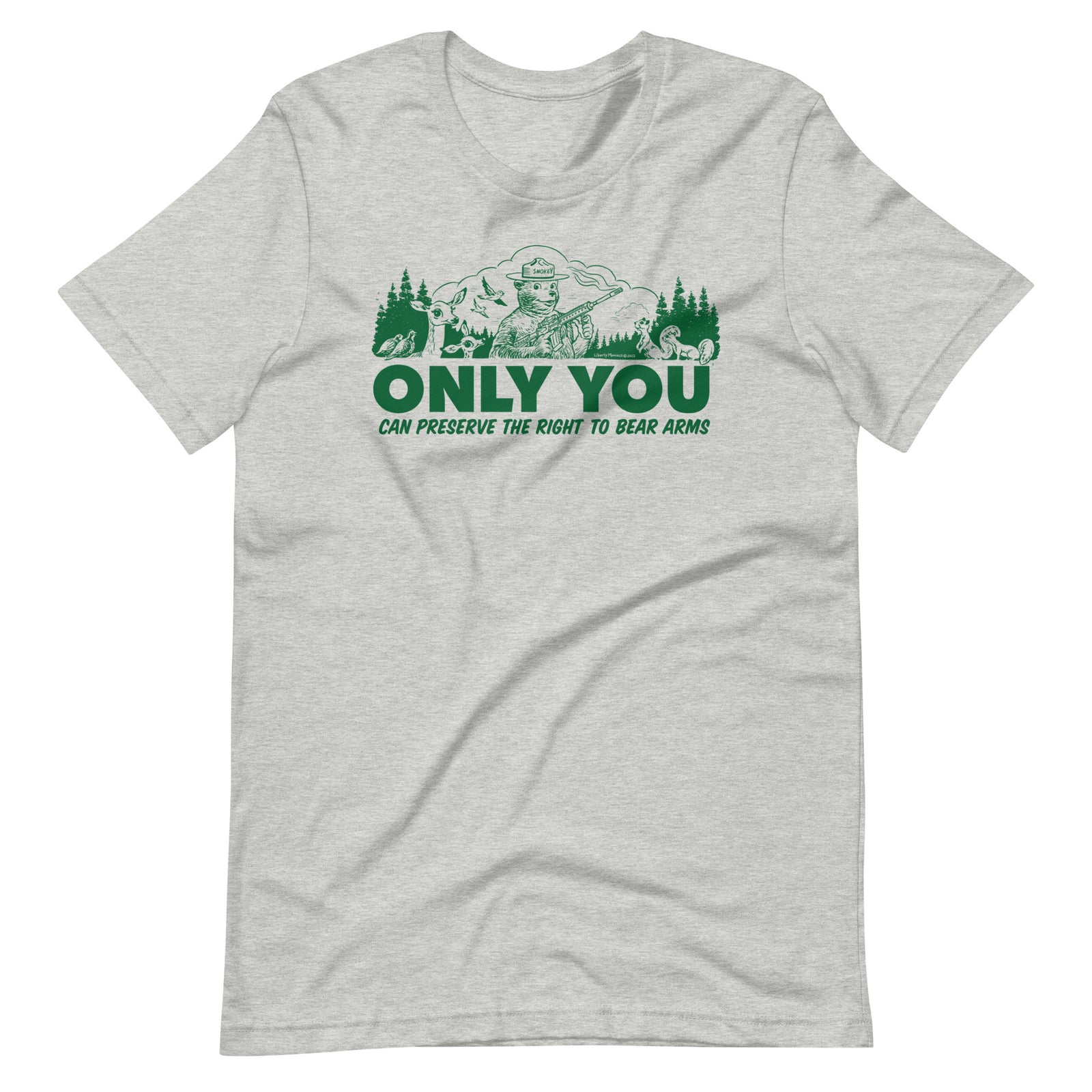 A heather gray t-shirt with a green graphic. The graphic shows a cartoon bear resembling Smokey Bear, wearing a ranger hat and holding a hunting rifle. The bear is centered in a forest setting with a deer, squirrels, and birds nearby. Below the image, large text reads, "ONLY YOU CAN PRESERVE THE RIGHT TO BEAR ARMS."