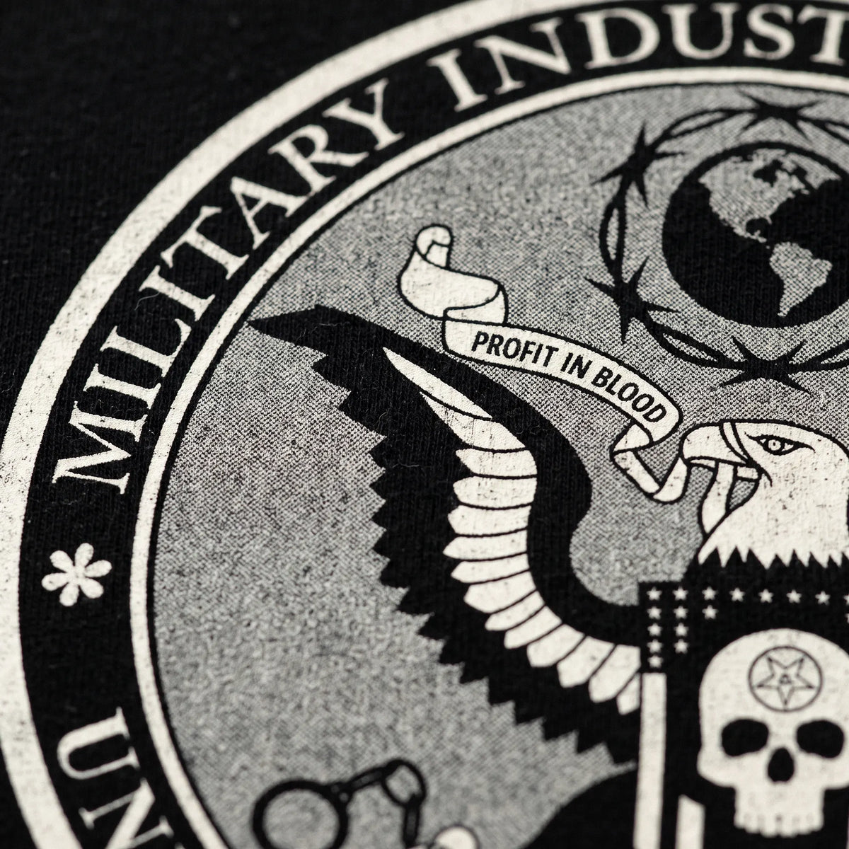Close-up of distressed Military Industrial Complex seal graphic on black boxy T-shirt