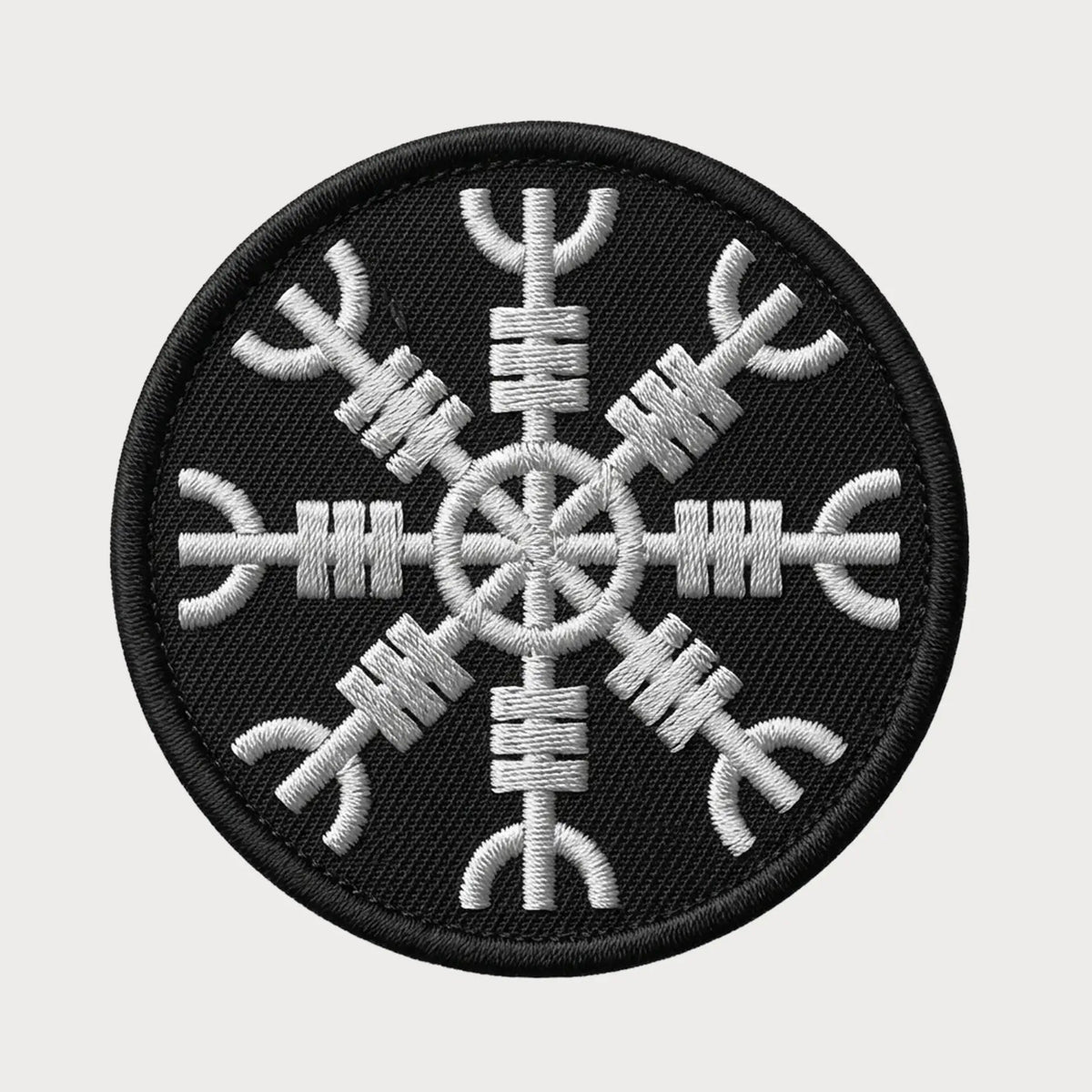 Black and white embroidered patch with a geometric design on a light gray background