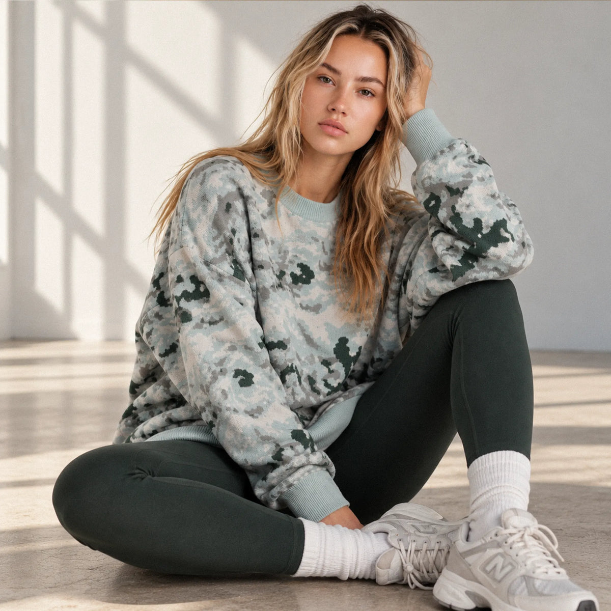 Blonde model wearing an oversized Arctic Splotch camouflage knit sweater in natural light