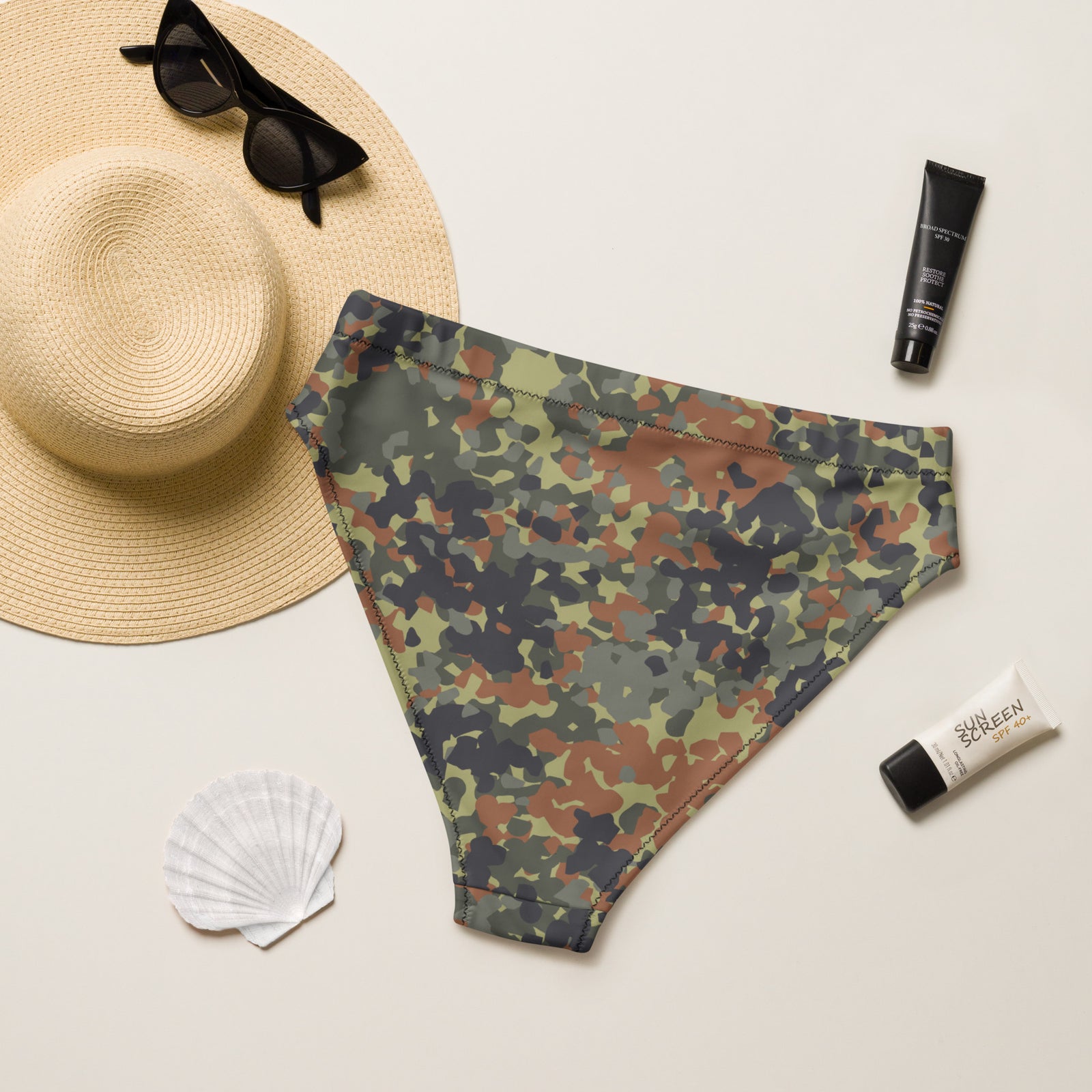 Camouflage swim trunks with a sun hat, sunglasses, and sunscreen on a light background