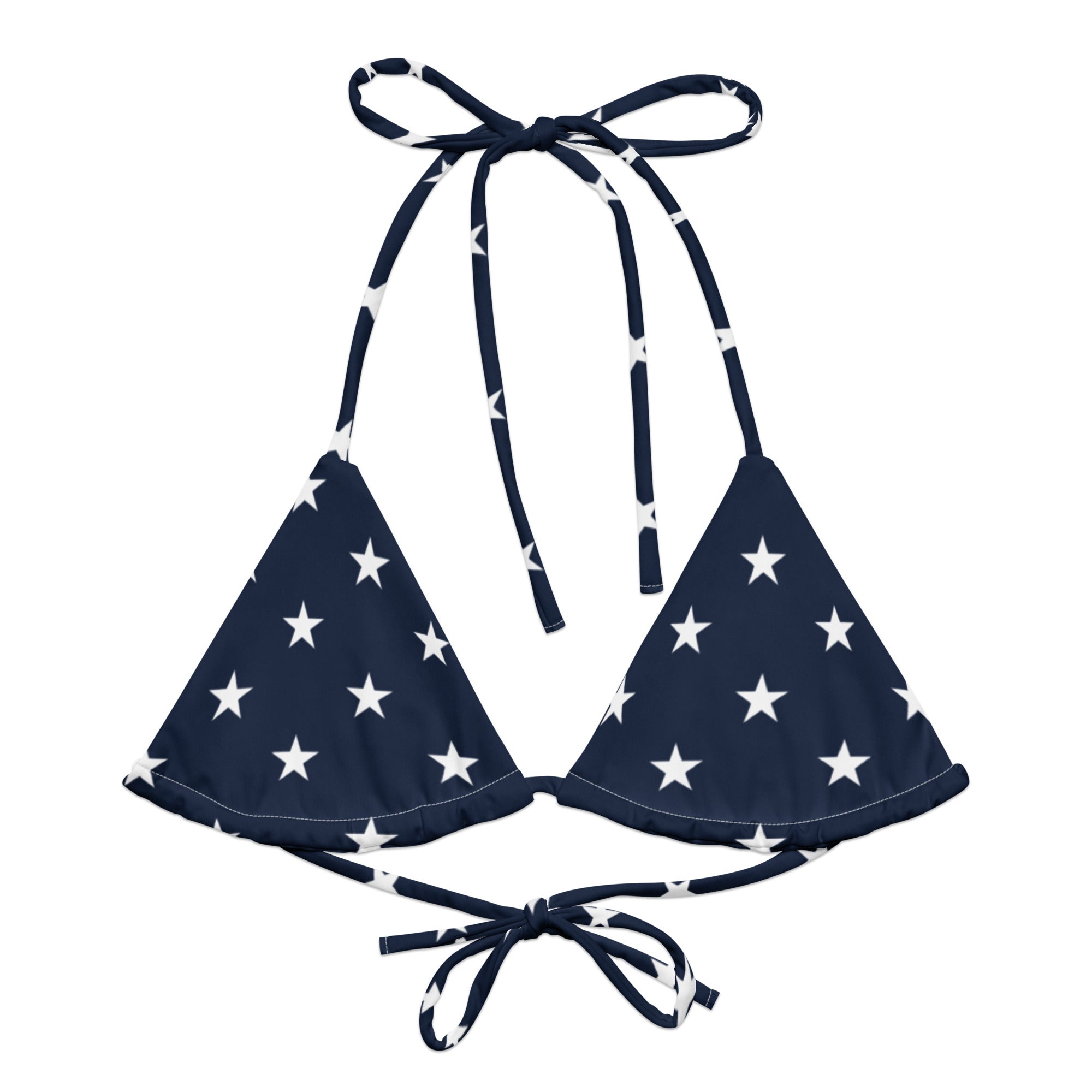 Woman wearing a navy blue bikini top with white star pattern on a gray background