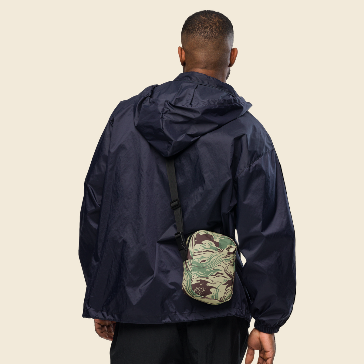 Person wearing a navy raincoat with a camouflage bag on a white background