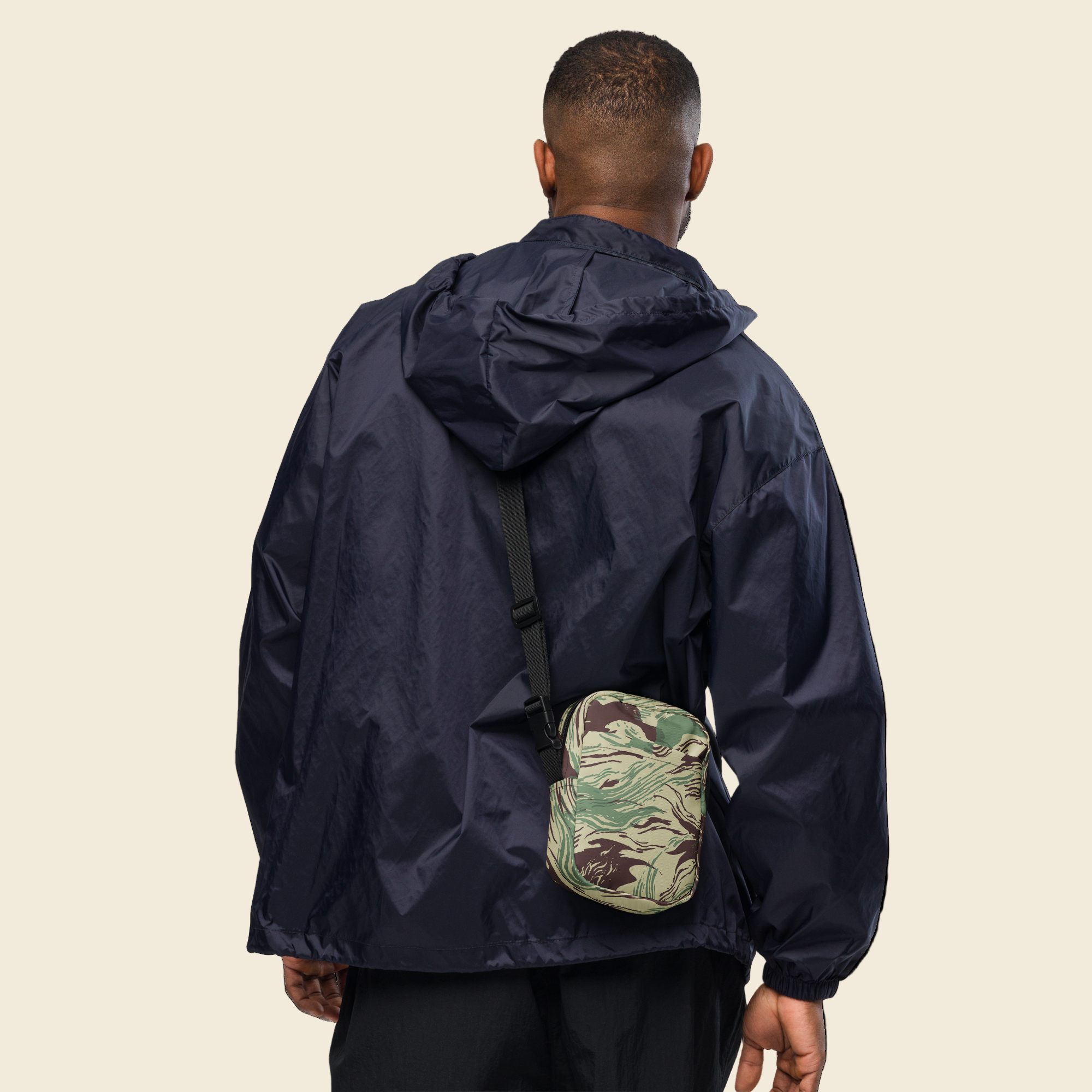 Person wearing a navy raincoat with a camouflage bag on a white background