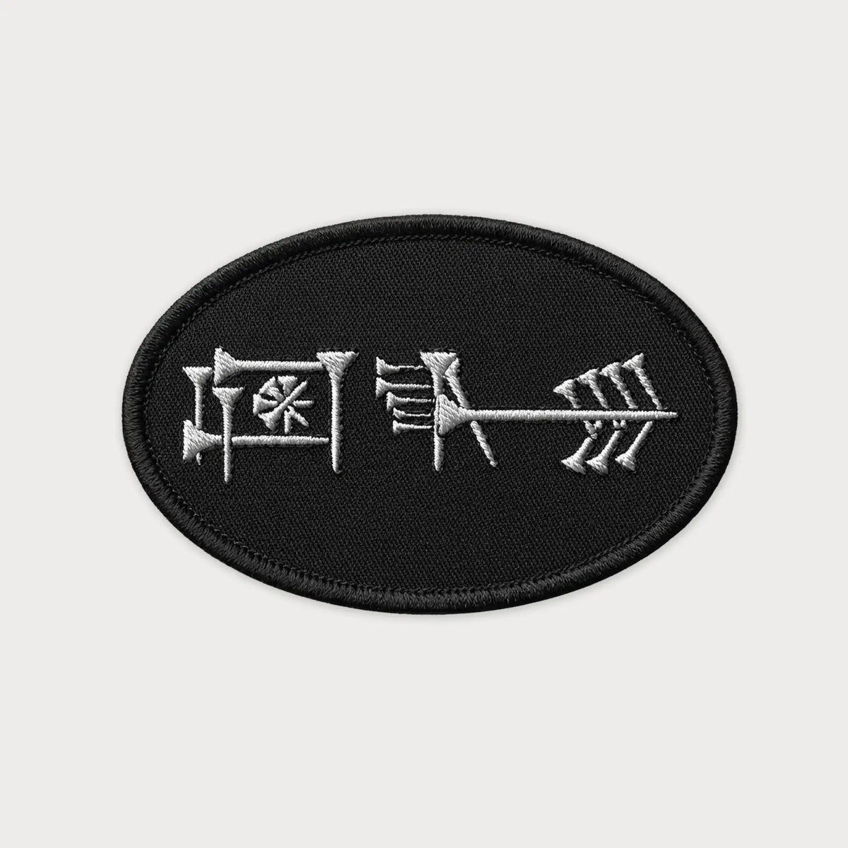 Black patch with white embroidered Ama-gi Cuneiform on a light gray background