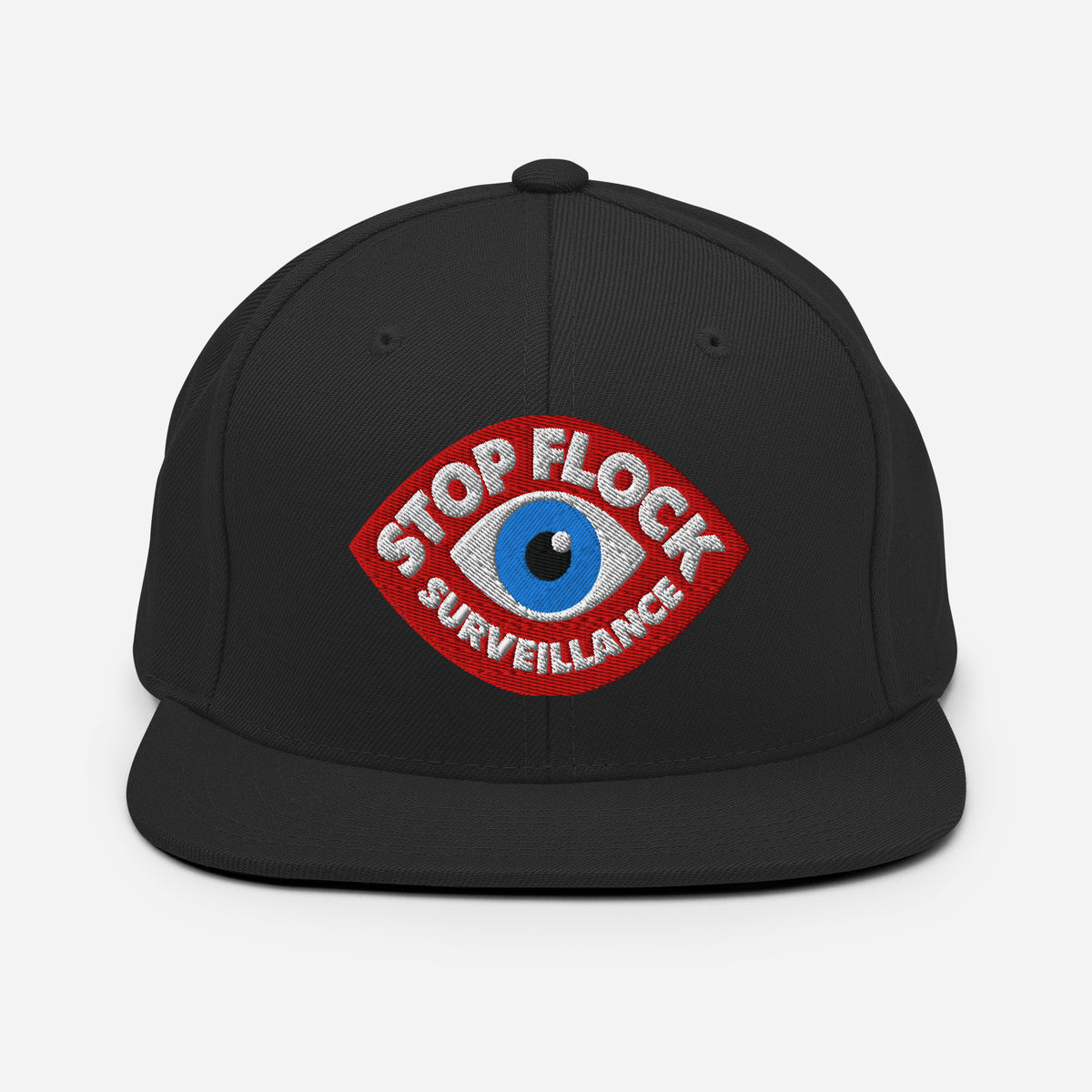 A black flat-brim snapback cap featuring a red embroidered patch on the front with a blue eye and the text 'STOP FLOCK SURVEILLANCE' in white.