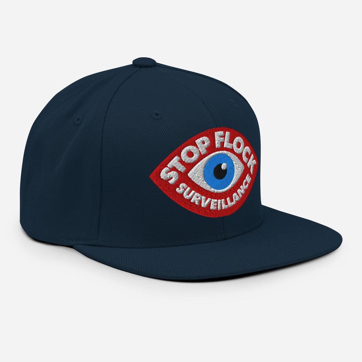 A dark navy blue flat-brim cap featuring a red and blue embroidered patch on the front with the text 'STOP FLOCK SURVEILLANCE' and an eye motif, set against a light gray background.