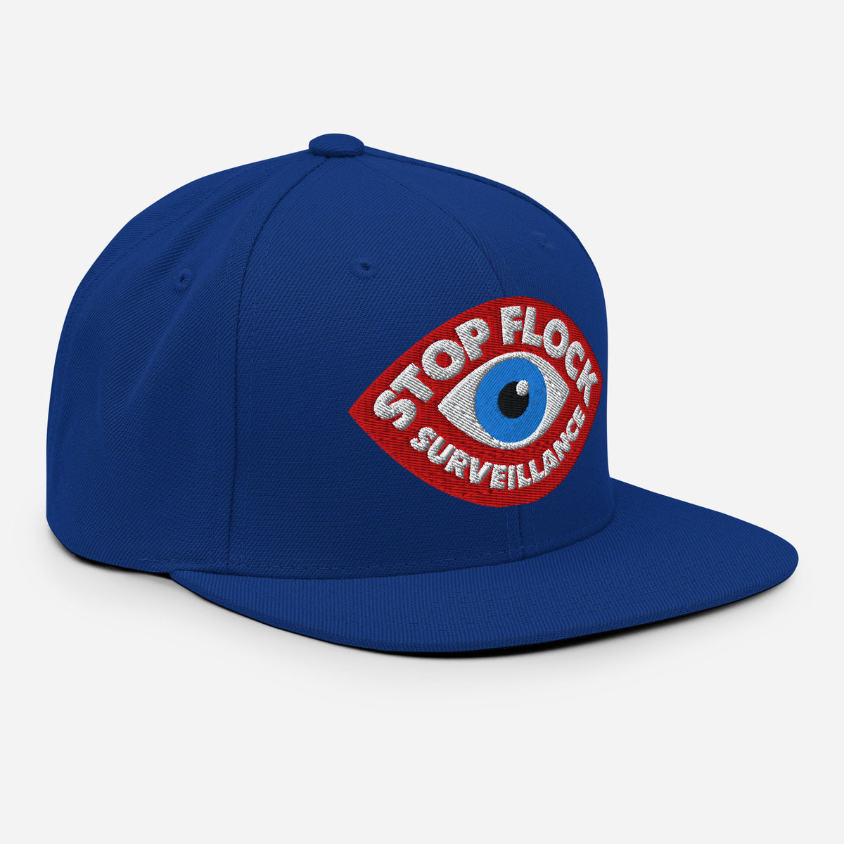 A royal blue flat-brim baseball cap featuring a red embroidered patch on the front with a blue eye and the text 'STOP FLOCK SURVEILLANCE' in white.
