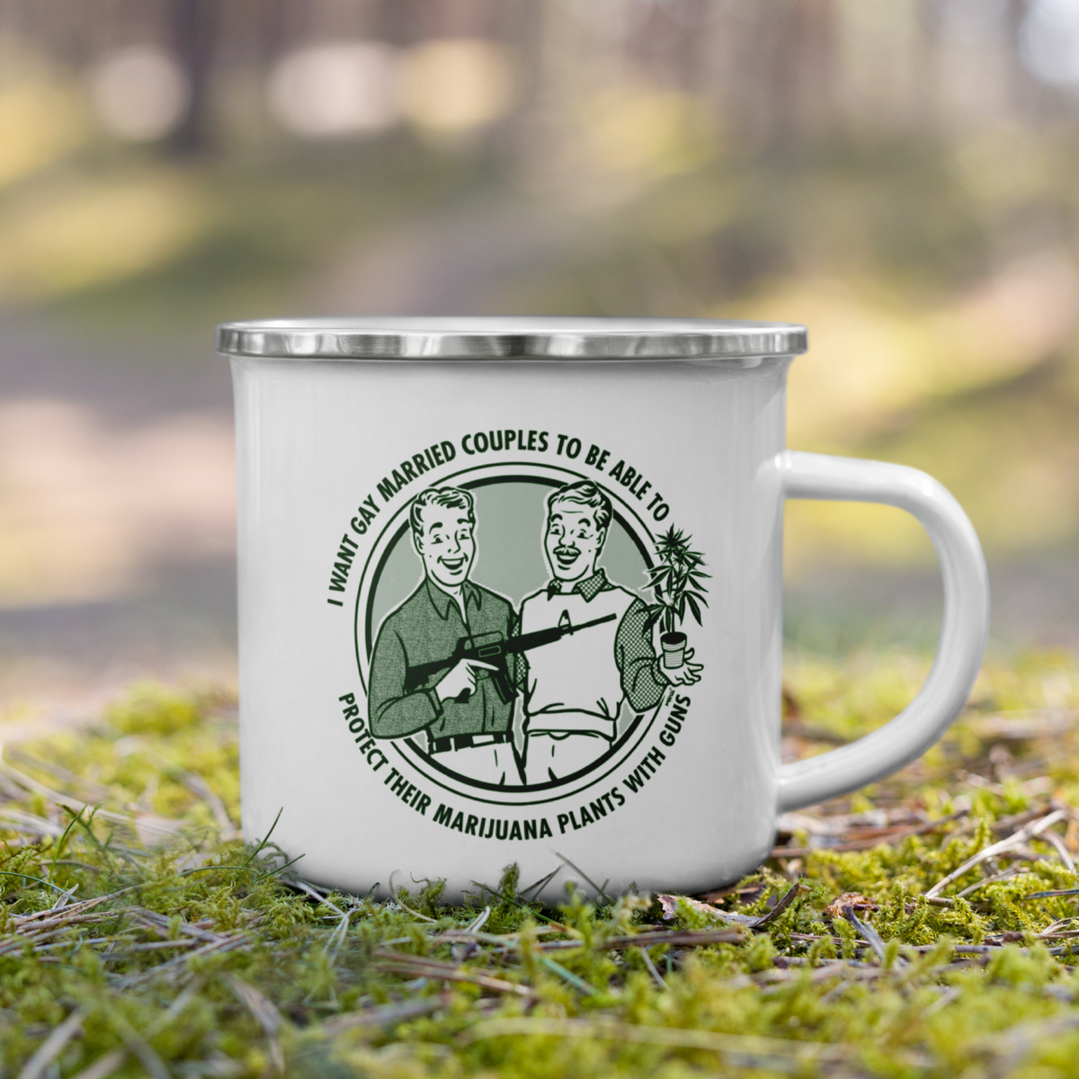A white enamel-style camping mug with a silver rim sits on green moss in a blurred forest setting. The mug has a circular green graphic and text that reads, 'I Want Gay Married Couples To Be Able To Protect Their Marijuana Plants With Guns