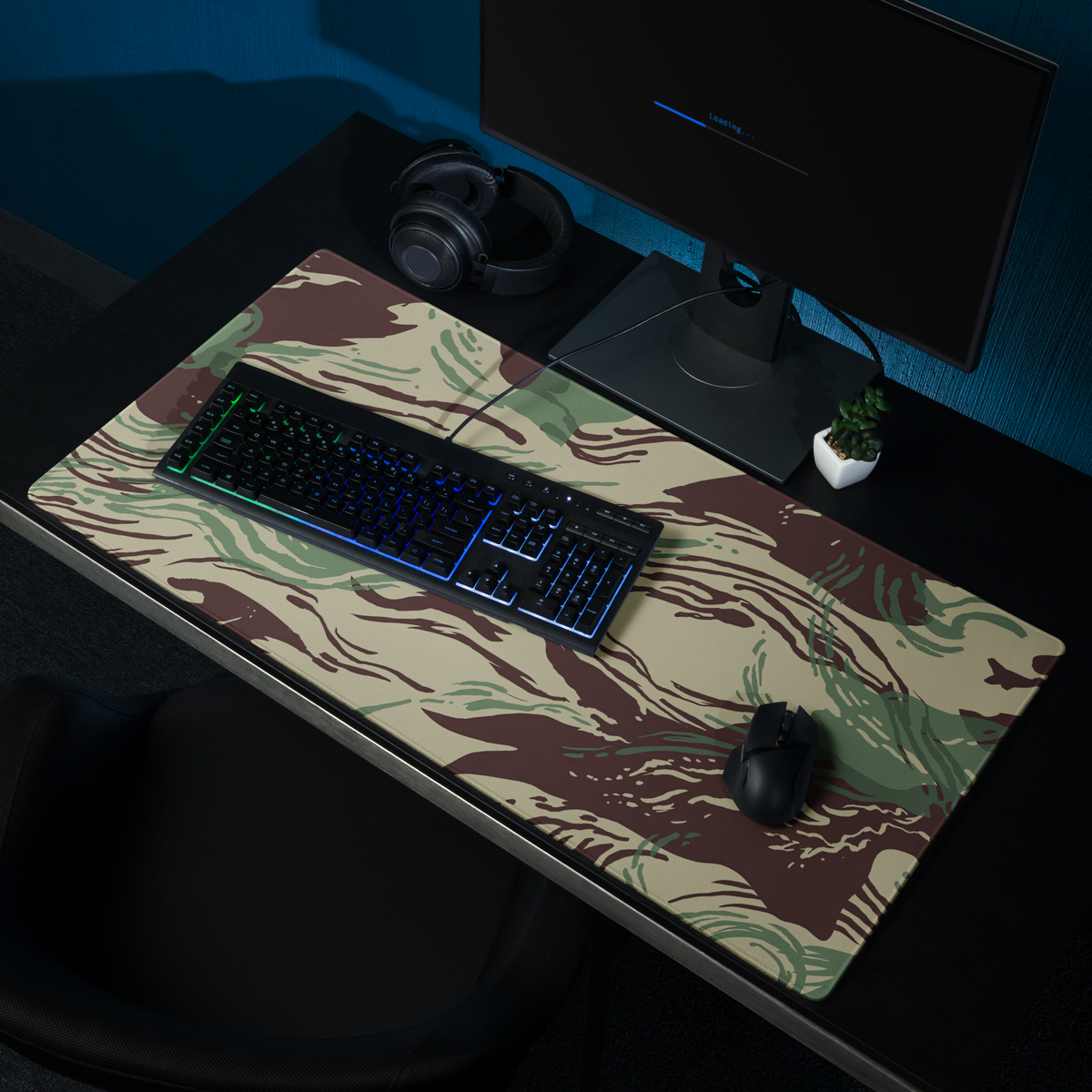 Camouflage desk mat with keyboard, mouse, and monitor on a dark desk.